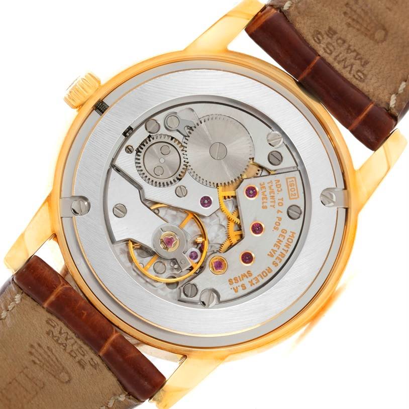 The image shows the back of a Rolex Cellini 5116 Men's Yellow Gold Grey Dial 5116 Men's Yellow Gold Grey Dial watch, revealing its internal mechanical movement and gears.