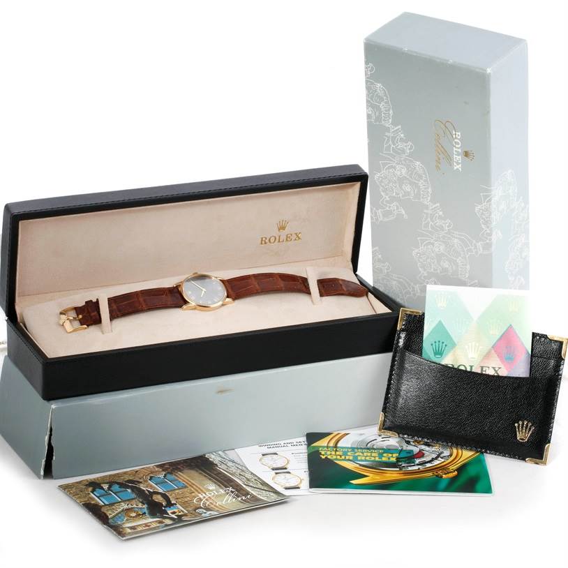 This image shows a Rolex Cellini 5116 Men's Yellow Gold Grey Dial 5116 Men's Yellow Gold Grey Dial watch in its original box, with associated packaging and booklets arranged around it.