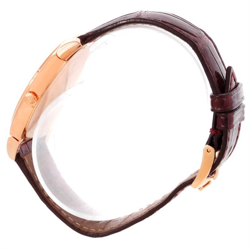 The Rolex Cellini 5330 Men's Rose Gold White Dial 5330 Men's Rose Gold White Dial watch is shown from a side angle, displaying its gold case and dark leather strap with a buckle.