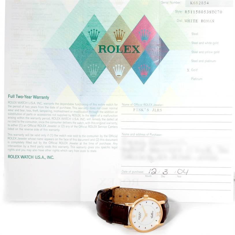 The image shows a Rolex Cellini 5115 Men
s Yellow Gold Silver Dial 5115 Men
s Yellow Gold Silver Dial watch with a brown leather strap, placed in front of warranty paperwork.