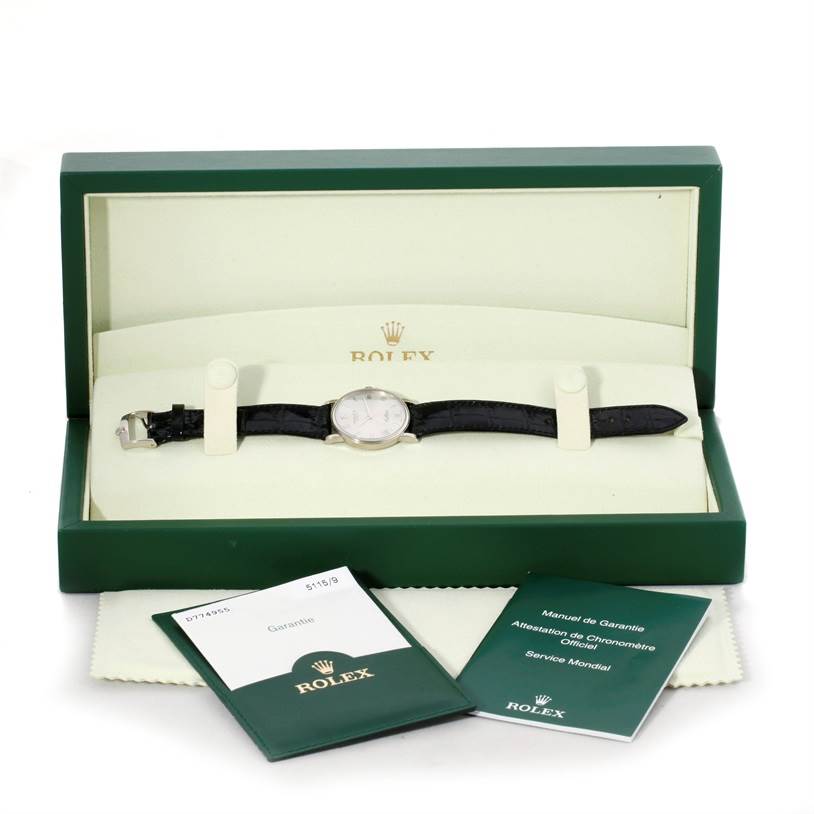 The image shows a Rolex Cellini 5115 Men's White Gold Silver Dial 5115 Men's White Gold Silver Dial watch lying flat in its open box, with accompanying booklets and cleaning cloth displayed in front.