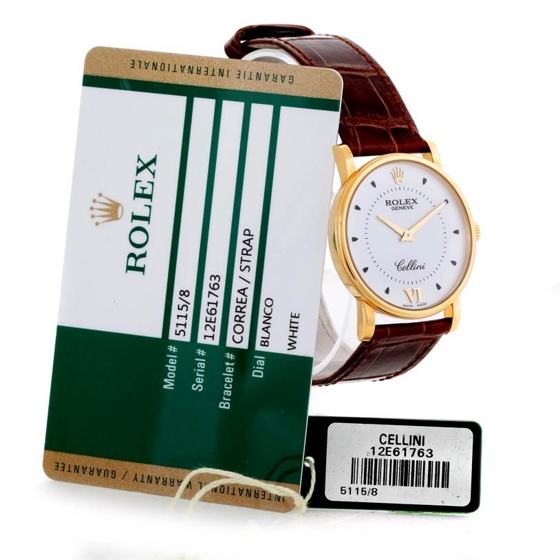 The Rolex Cellini 5115 Men
s Yellow Gold Silver Dial 5115 Men
s Yellow Gold Silver Dial watch is shown at an angled view displaying its white dial and brown leather strap, accompanied by its model and serial tags.