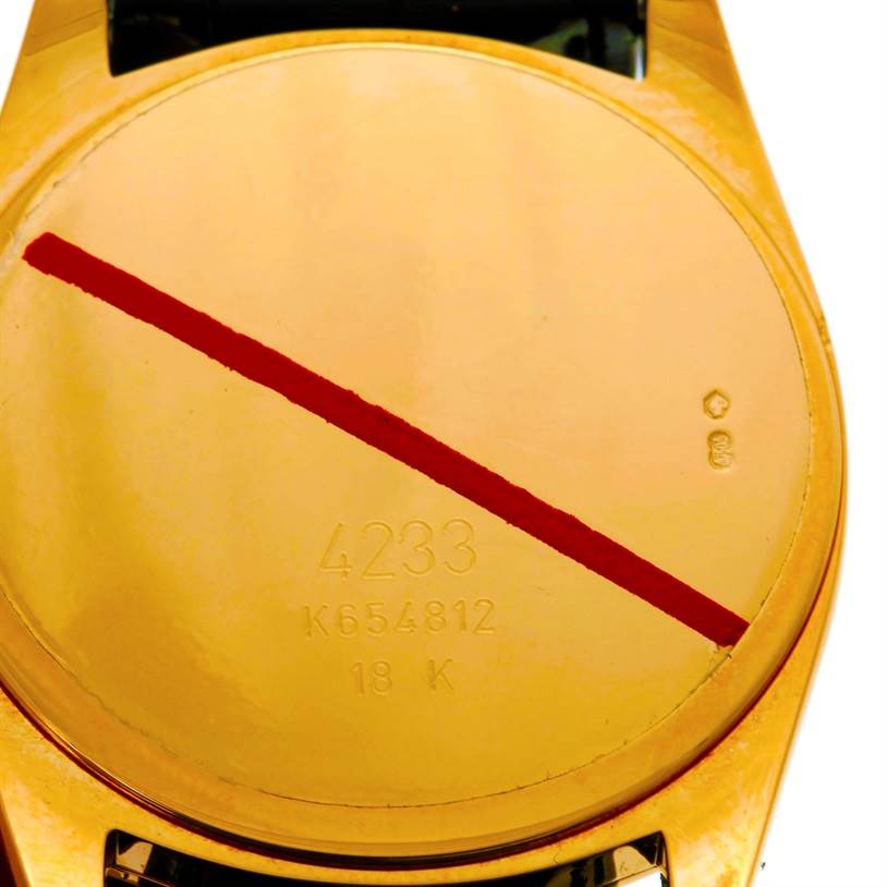 The image shows the back case of a Rolex Cellini 4233 Men
s Yellow Gold Black Dial 4233 Men
s Yellow Gold Black Dial watch, featuring engravings and a red line across it.