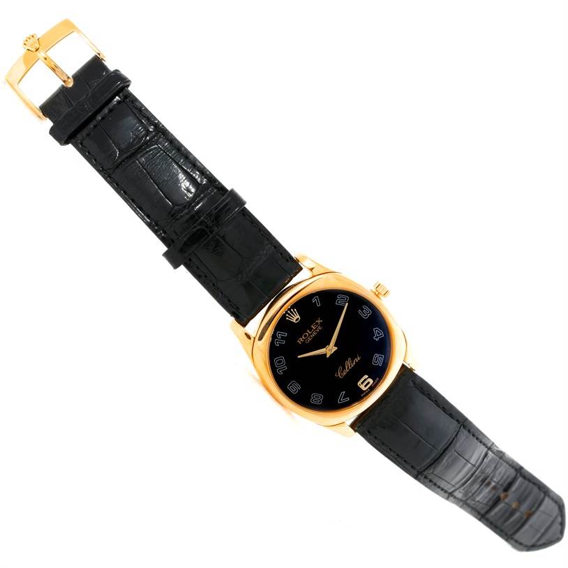 The image shows a top view of a Rolex Cellini 4233 Men
s Yellow Gold Black Dial 4233 Men
s Yellow Gold Black Dial watch with a black leather strap and a gold case.