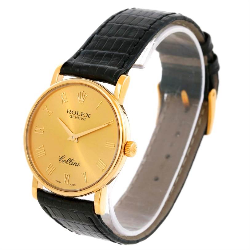 The Rolex Cellini 5115 Men
s Yellow Gold Champagne Dial 5115 Men
s Yellow Gold Champagne Dial watch is shown at a slight angle, focusing on the gold face, hands, Roman numerals, and black leather strap.
