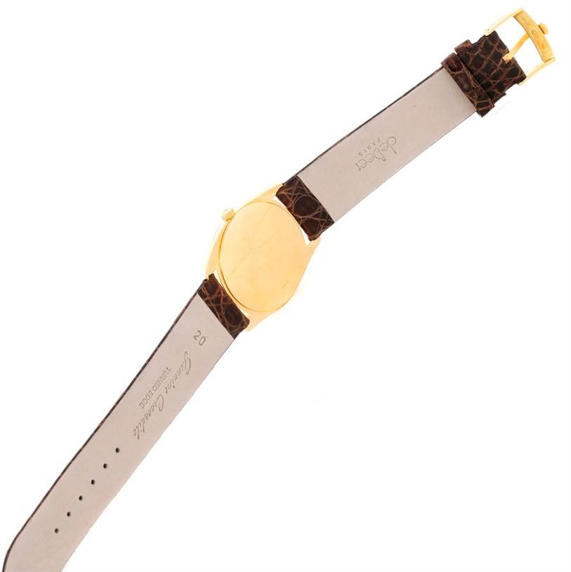 The image shows a Rolex Cellini 4233 Men
s Yellow Gold White Dial 4233 Men
s Yellow Gold White Dial watch from a back angle, displaying its gold case and brown leather strap.