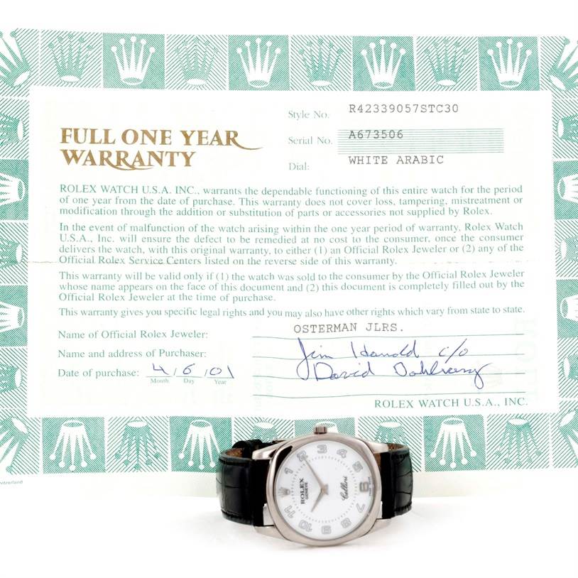 The image shows a Rolex Cellini 4233 Men's White Gold White Dial 4233 Men's White Gold White Dial watch with a white face and black leather band, placed in front of a full one-year warranty document.