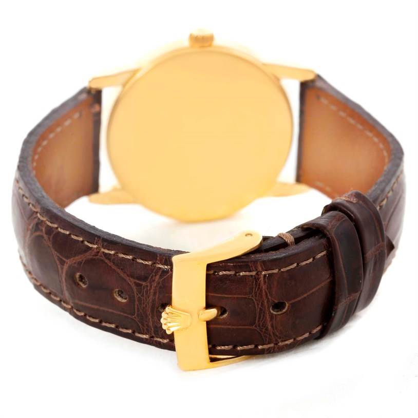 The image shows the back side of a Rolex Cellini 5116 Men
s Yellow Gold Black Dial 5116 Men
s Yellow Gold Black Dial watch, highlighting its leather strap and gold-colored buckle.