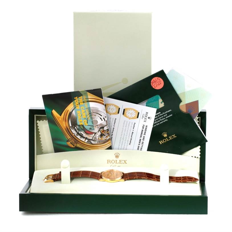 The image shows a Rolex Cellini 5116 Men
s Yellow Gold Champagne Dial 5116 Men
s Yellow Gold Champagne Dial watch lying flat in its box, along with accompanying documentation and accessories.