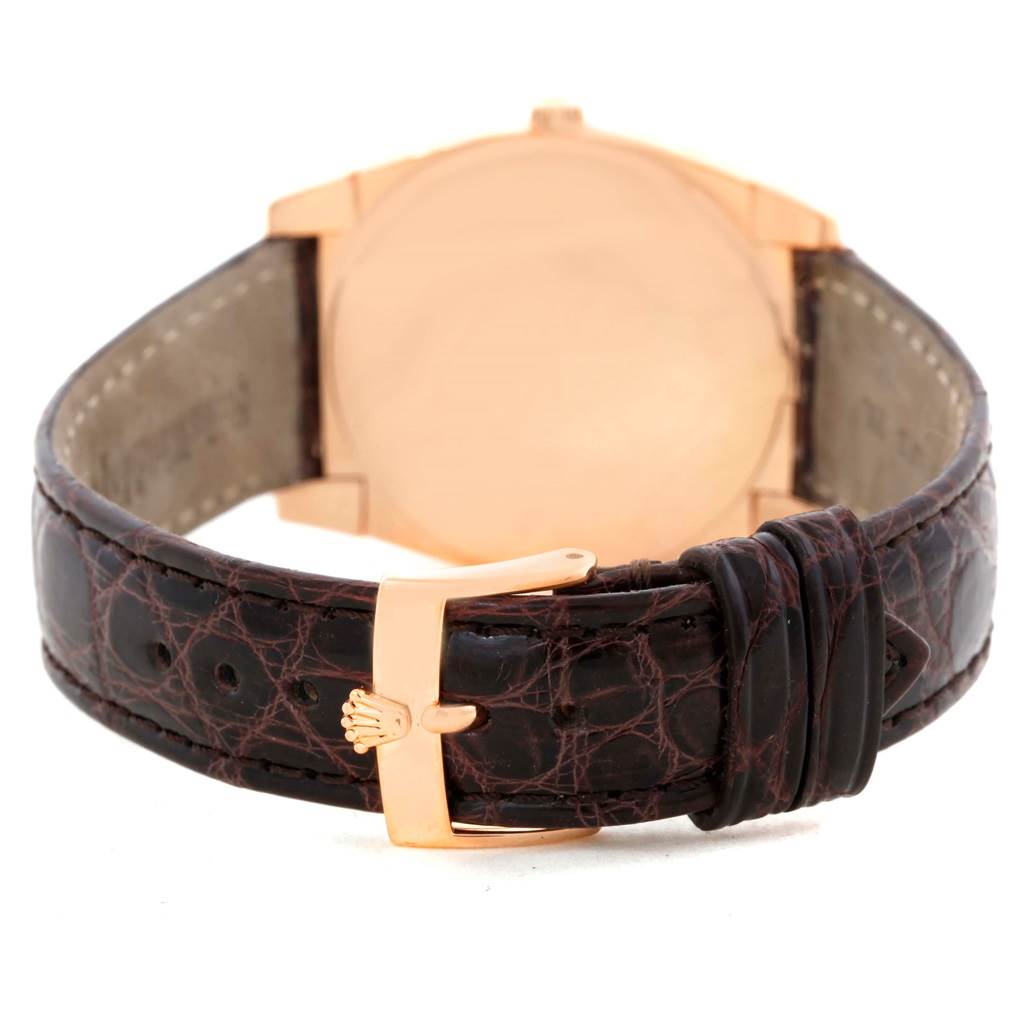 The image shows the back view of a Rolex Cellini 5330 Men's Rose Gold White Dial 5330 Men's Rose Gold White Dial watch, featuring its leather strap and golden buckle with the Rolex emblem.