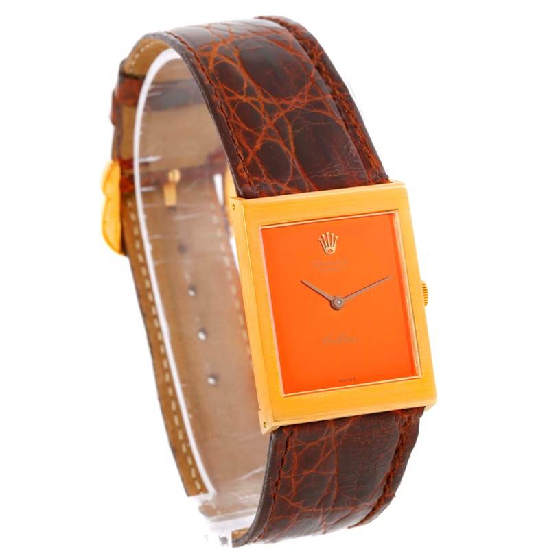 The Rolex Cellini 4014 Men's Yellow Gold Orange Dial 4014 Men's Yellow Gold Orange Dial watch is shown at an angled side view, displaying its rectangular face, orange dial, and textured brown leather strap.