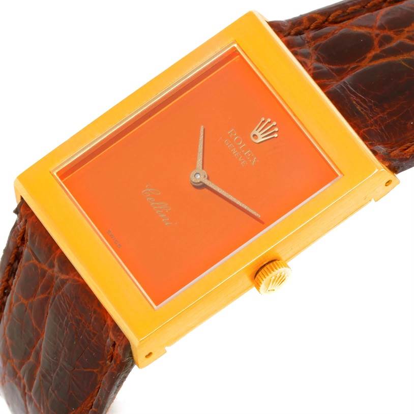 The watch is at a slight angle showing the face, crown, and part of the leather strap of the Rolex Cellini 4014 Men's Yellow Gold Orange Dial 4014 Men's Yellow Gold Orange Dial model.