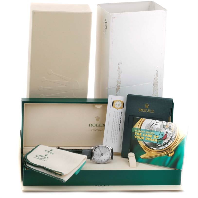 The image shows the Rolex Cellini 4243/8 Men
s White Gold Silver Dial 4243/8 Men
s White Gold Silver Dial watch in its open box, accompanied by a booklet, warranty card, and a cleaning cloth.