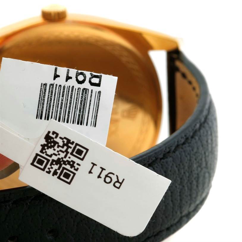 This image of a Rolex Cellini 4243 Men's Yellow Gold Champagne Dial 4243 Men's Yellow Gold Champagne Dial watch shows the back case and leather strap with attached tags including barcodes.