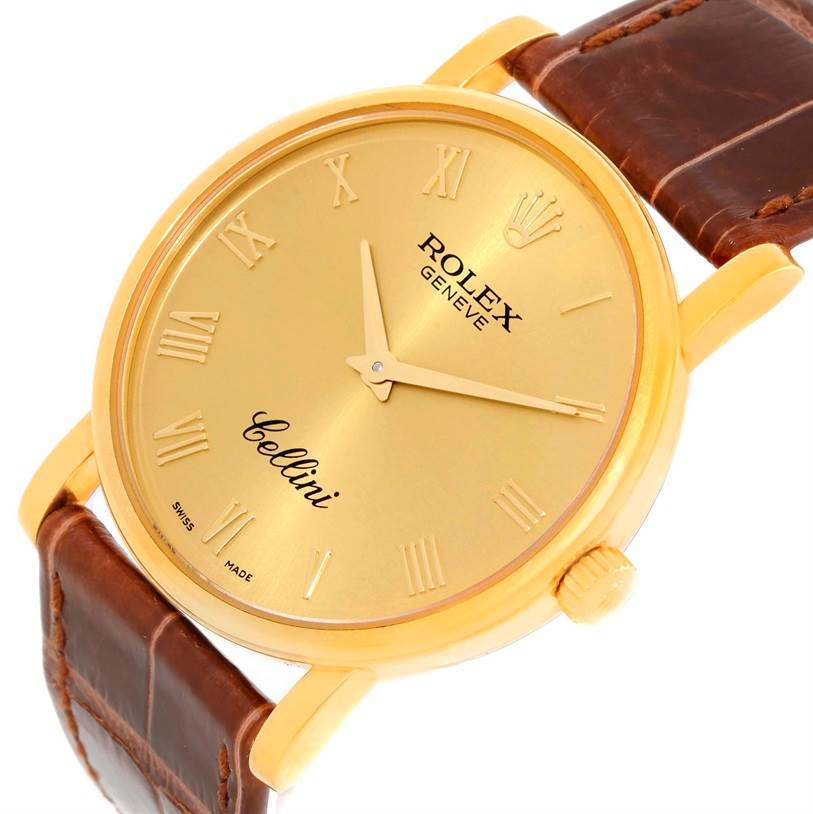 The image shows a Rolex Cellini 5115 Men
s Yellow Gold Champagne Dial 5115 Men
s Yellow Gold Champagne Dial watch at an oblique angle, highlighting the gold dial, Roman numerals, and brown leather strap.