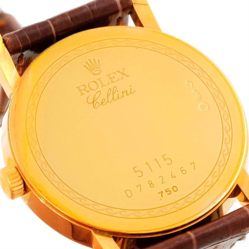 The image shows the back case of a Rolex Cellini 5115 Men
s Yellow Gold Champagne Dial 5115 Men
s Yellow Gold Champagne Dial model watch, including its engraved details and a portion of the brown leather strap.