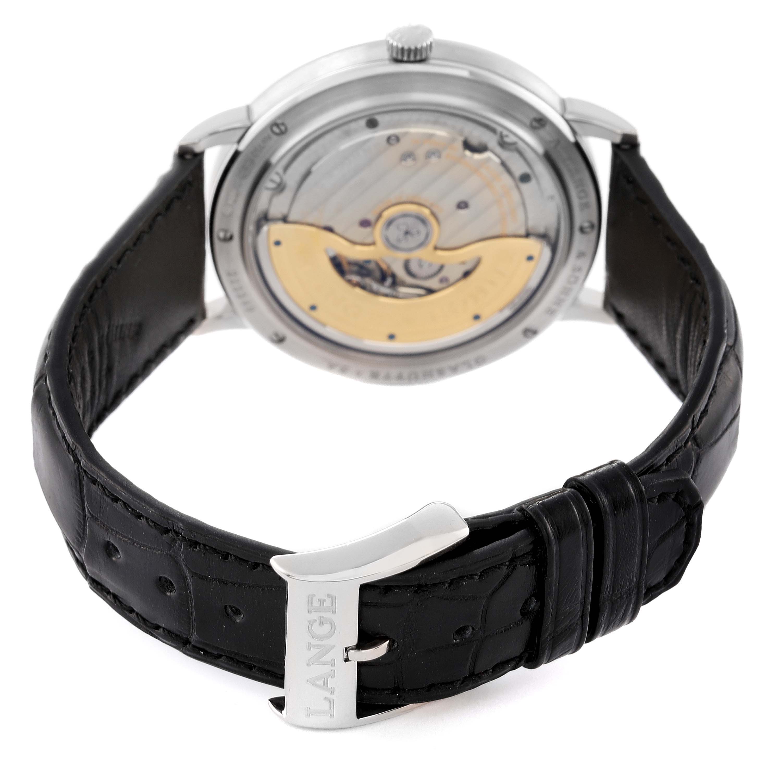 The image shows the back view of the A. Lange & Sohne Saxonia 380.027 Men's White Gold Silver Dial watch, highlighting its automatic movement and black leather strap.