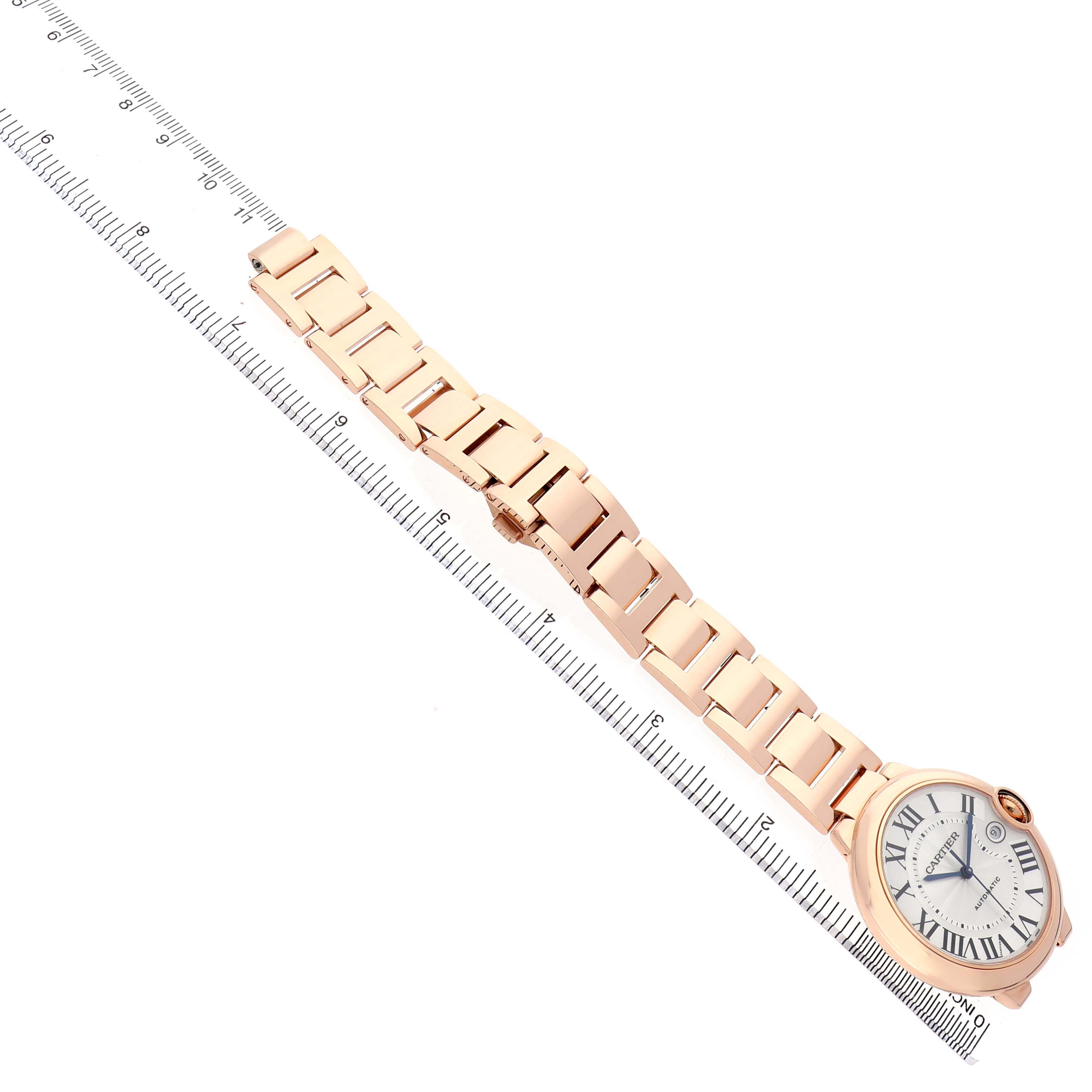 The image shows the Ballon Bleu by Cartier flat at an angle, displaying its face, bracelet, and deployment clasp alongside a ruler.