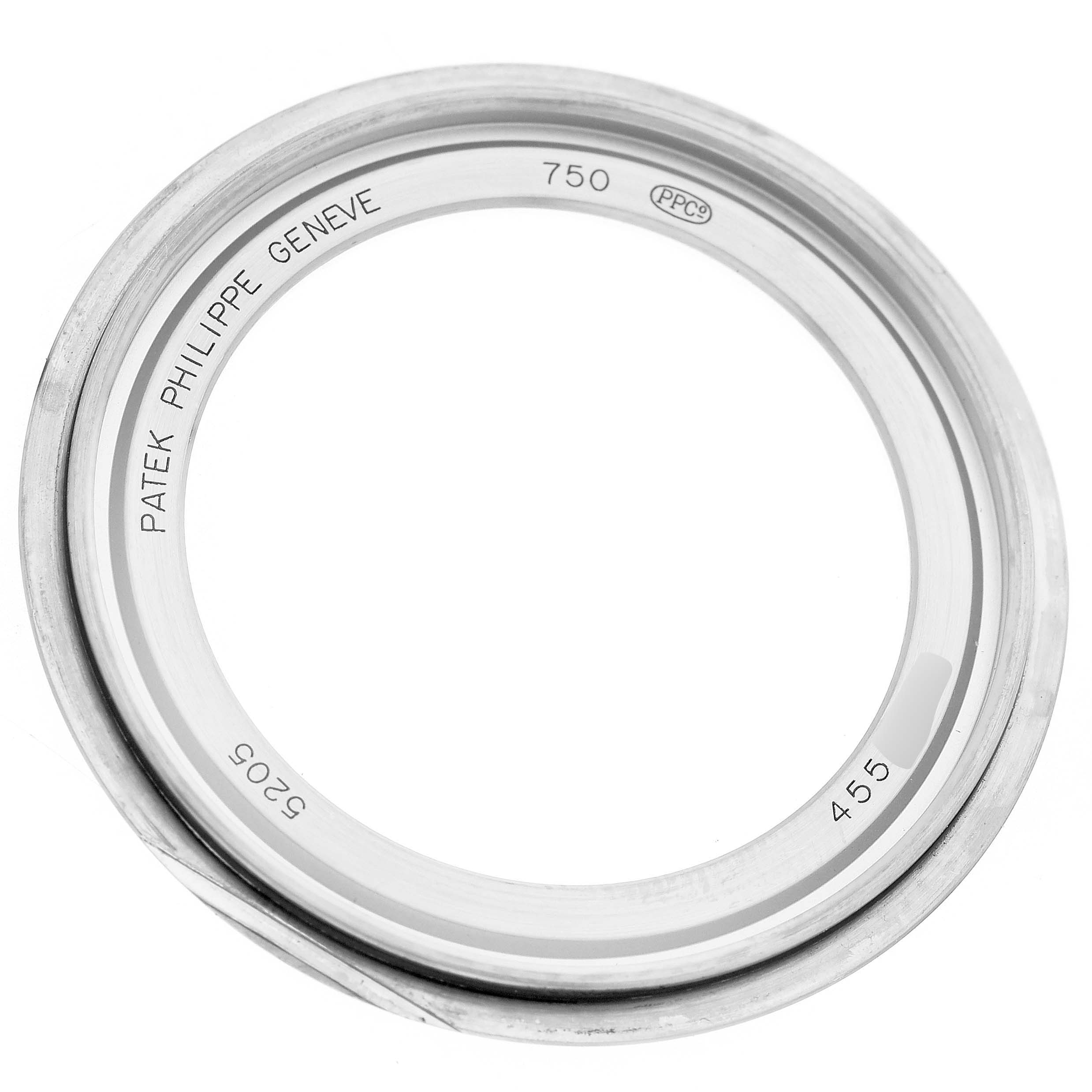 The image shows the bezel of a Patek Philippe Complications 5205G-010 Men's White Gold Grey Dial watch, viewed from above, displaying engravings and markings.