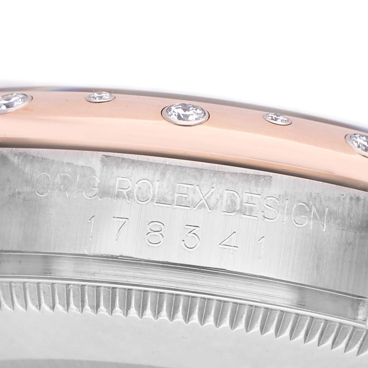 The image shows a close-up of the side view of the bezel and case of a Mid-Size Rolex watch, highlighting the engraved design and diamonds.