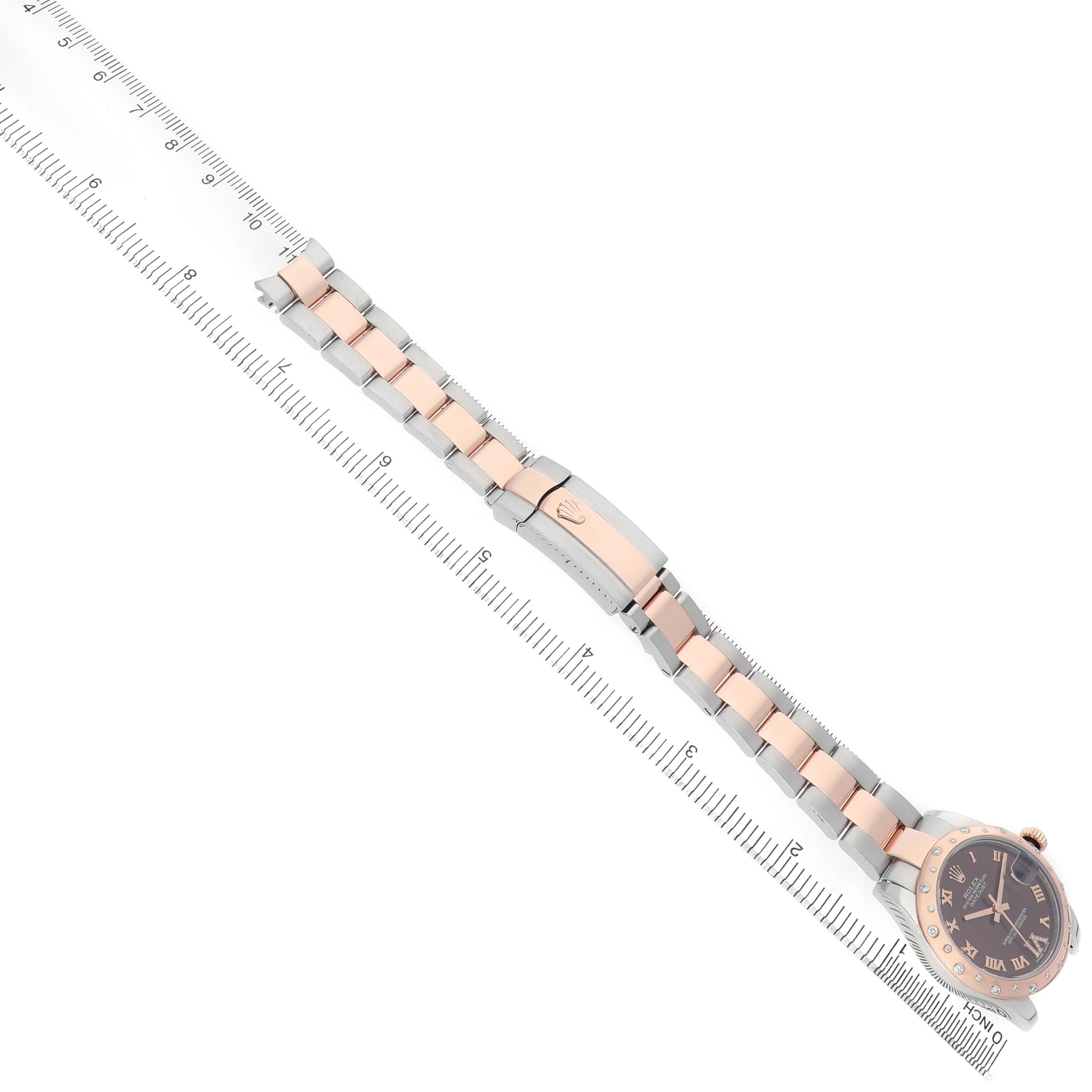 The Rolex Mid-Size 178341 Women's Steel and Gold (two tone) Brown Dial watch is shown at a diagonal angle, displaying the entire bracelet, clasp, and face next to a ruler.