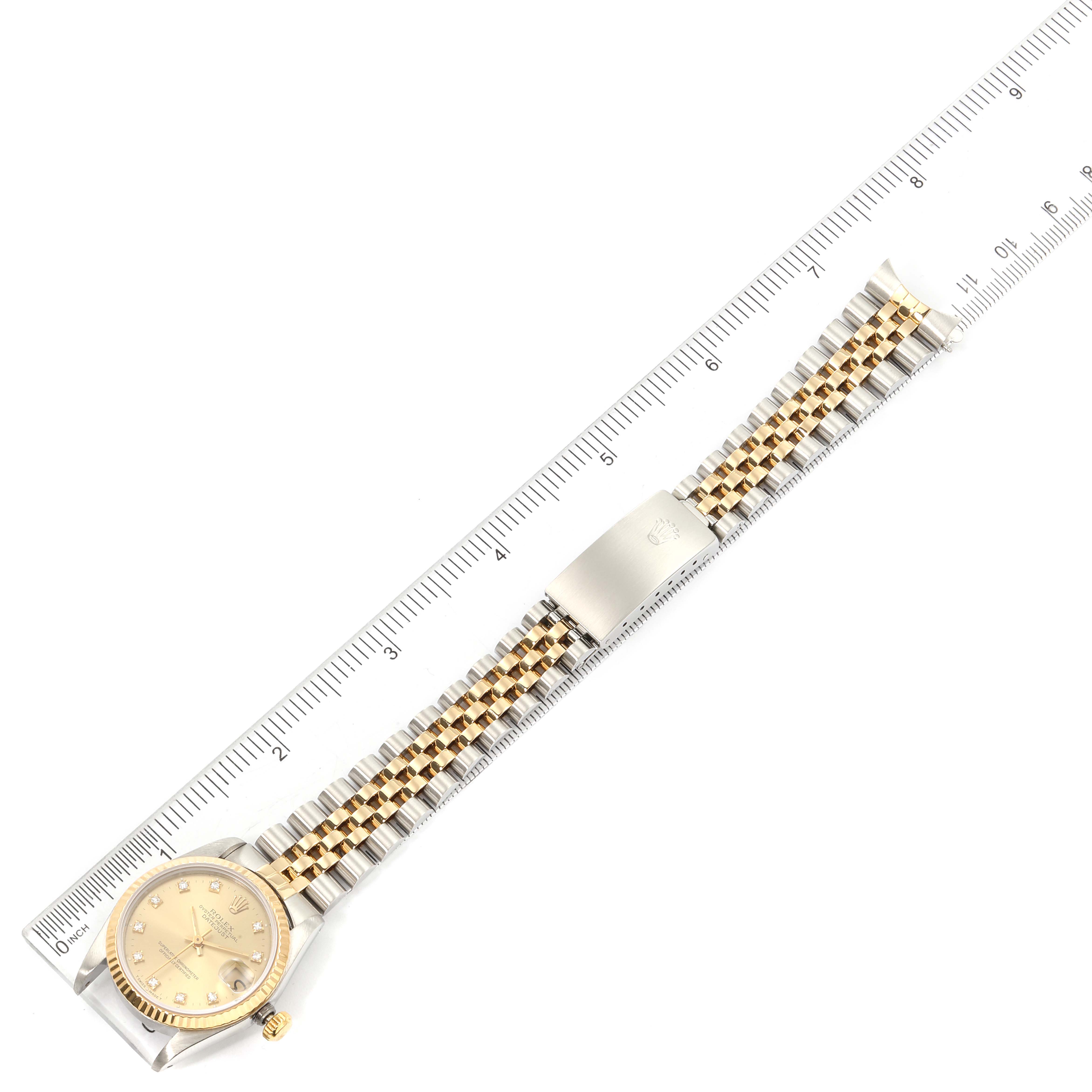 The Rolex Mid-Size 68273 Women's Steel and Gold (two tone) Champagne Dial 68273 Women's Steel and Gold (two tone) Champagne Dial watch is shown from a top-down angle, displaying the dial, two-tone bracelet, and clasp alongside a ruler for scale.