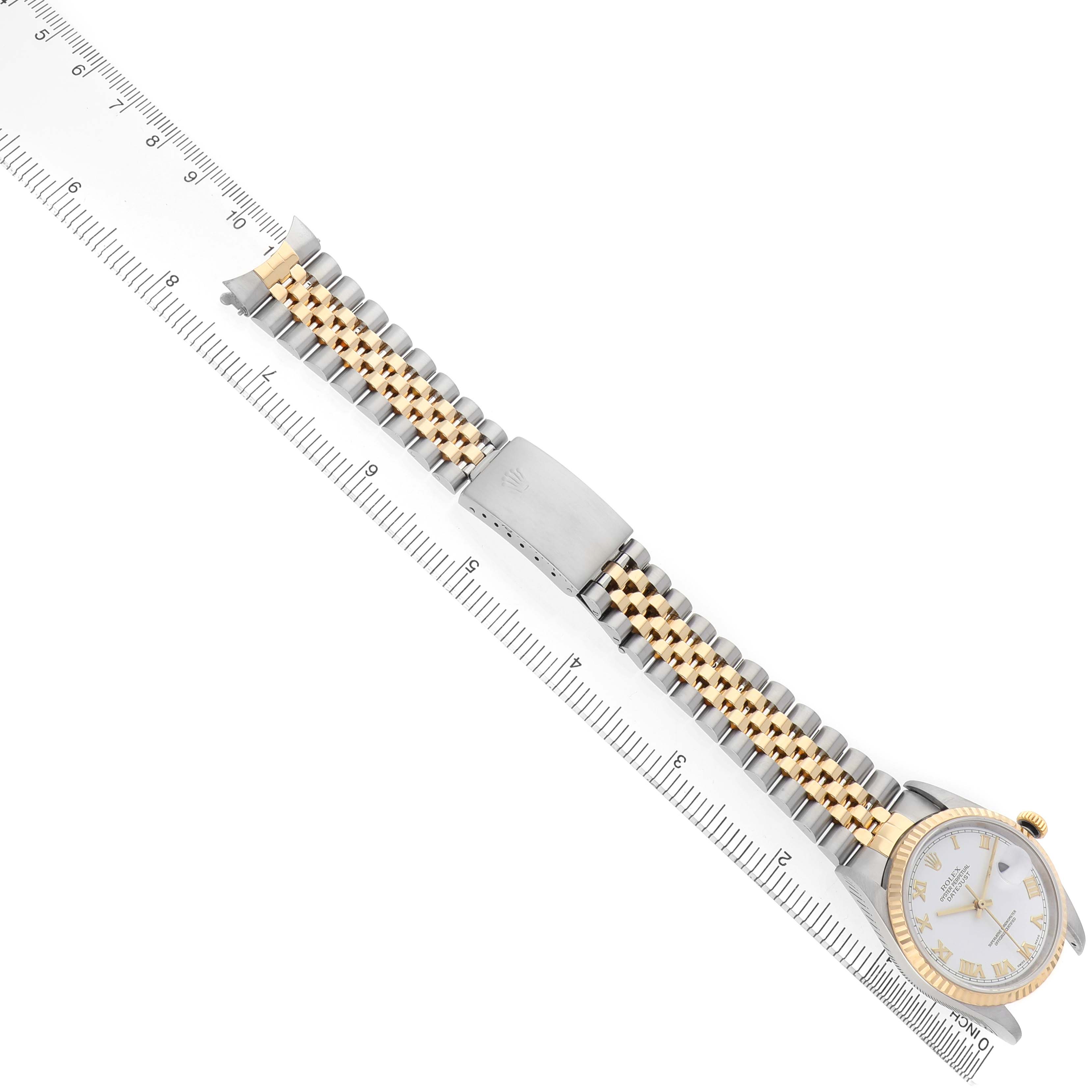 The Rolex Datejust 16233 Men's Steel and Gold (two tone) White Dial watch is shown face up with its bracelet extended along a ruler.
