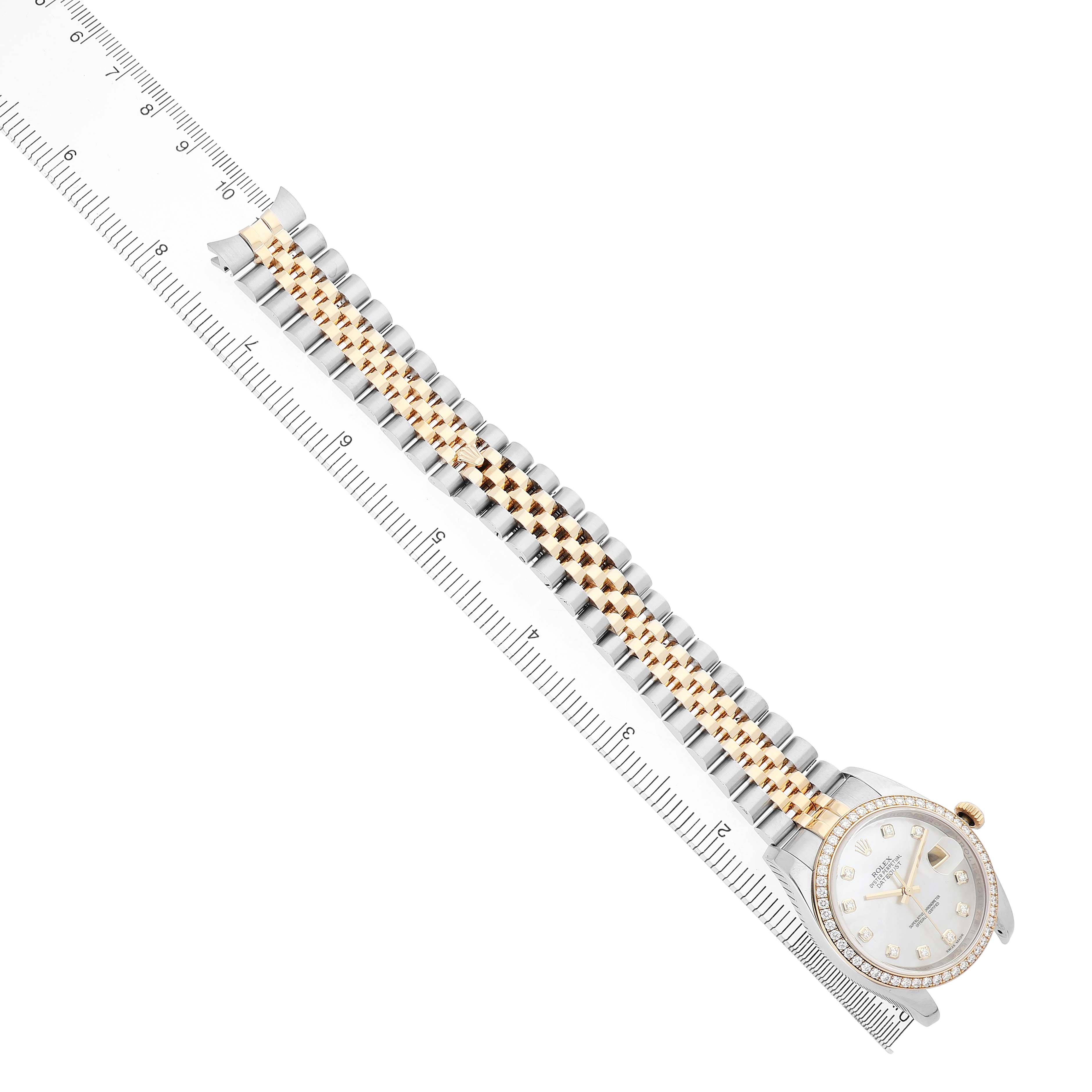 The image shows a Rolex Datejust 116243 Men's Steel and Gold (two tone) Mother of Pearl Dial watch laid flat, highlighting the face, bezel, and two-tone bracelet, alongside a ruler.