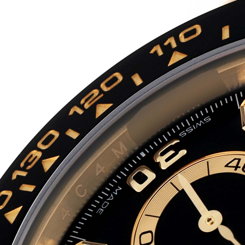 This image shows a close-up of the bezel and part of the dial of a Rolex Daytona 116518 Men's Yellow Gold Black Dial 116518 Men's Yellow Gold Black Dial watch.