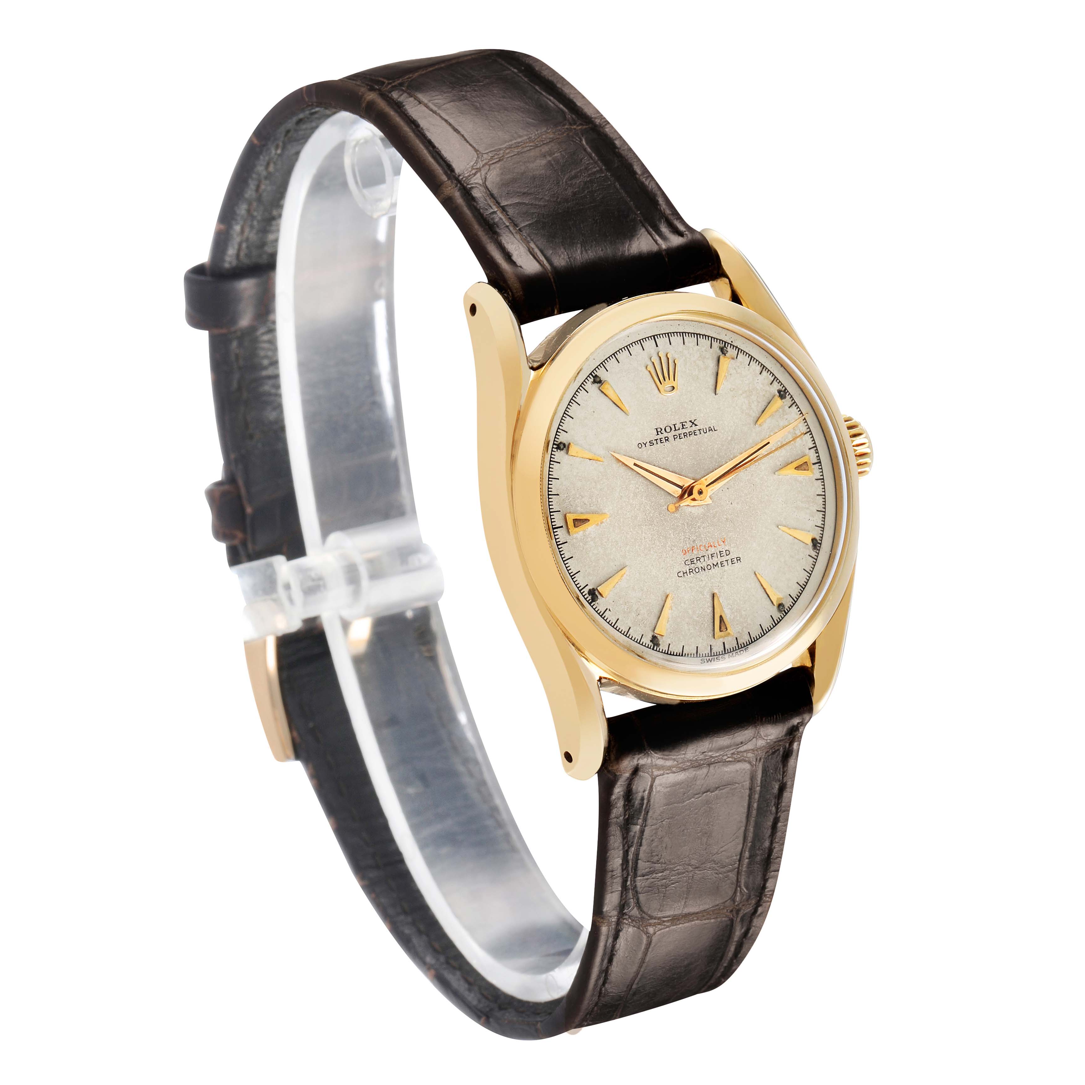 The Rolex Oyster Perpetual 6085 Men's Yellow Gold Champagne Dial watch is shown at a slight side angle, highlighting the face, gold bezel, and brown leather strap.