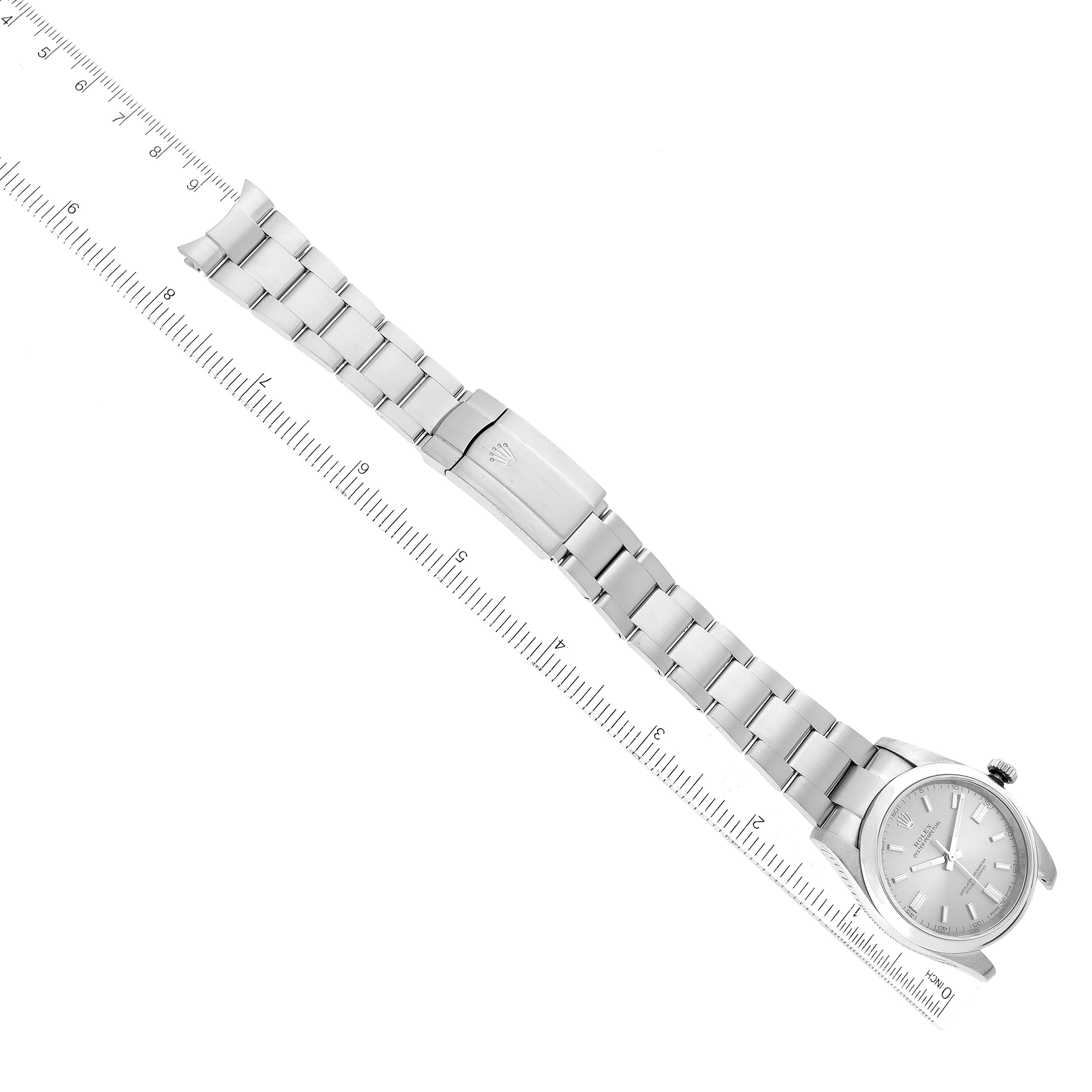 The image shows a Rolex Oyster Perpetual 116000 Men's Stainless Steel Silver Dial 116000 Men's Stainless Steel Silver Dial watch flat and fully extended with a ruler next to it for scale.