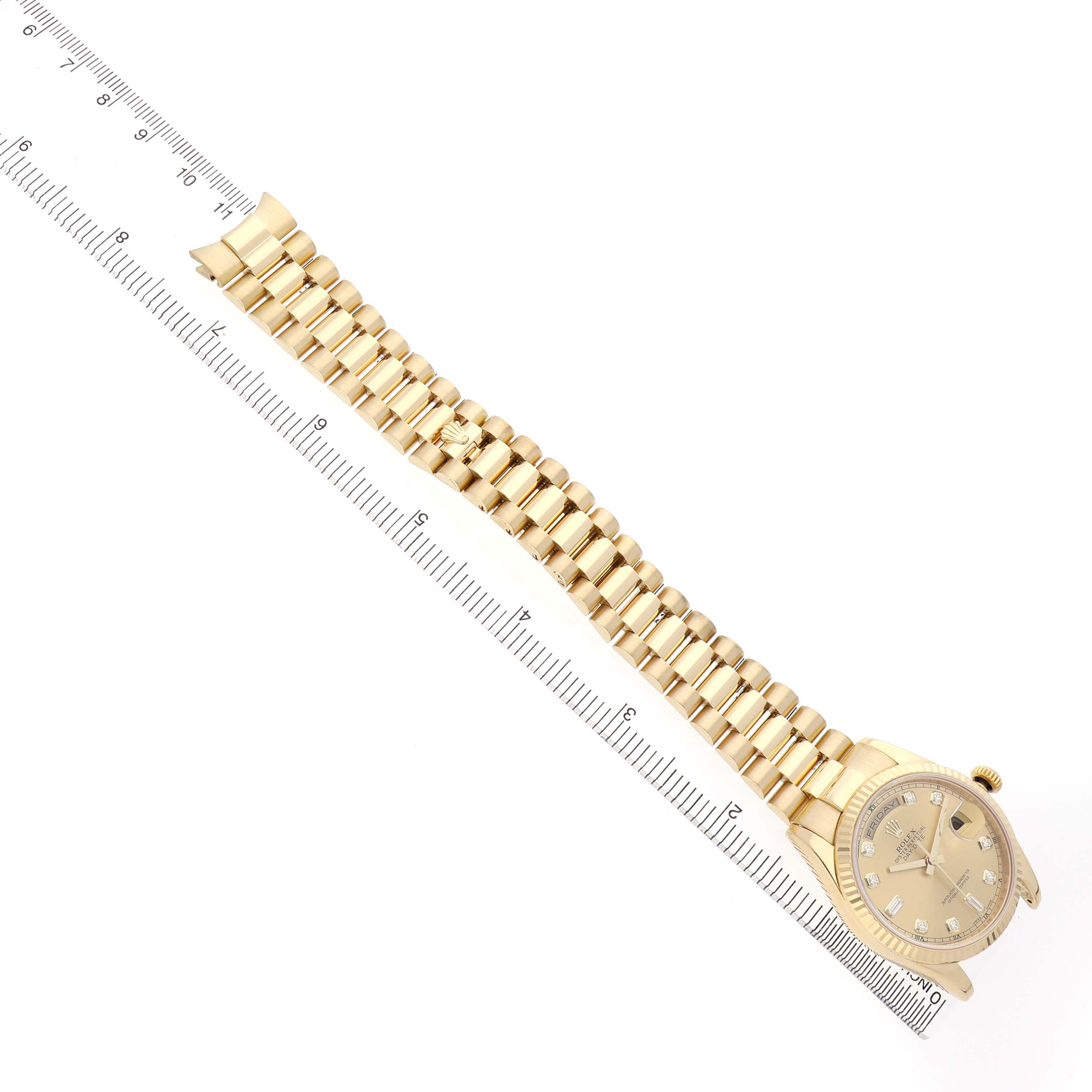 The Rolex President 118238 Men's Yellow Gold Champagne Dial watch is shown from an overhead angle, highlighting the bracelet and face alongside a ruler for scale.