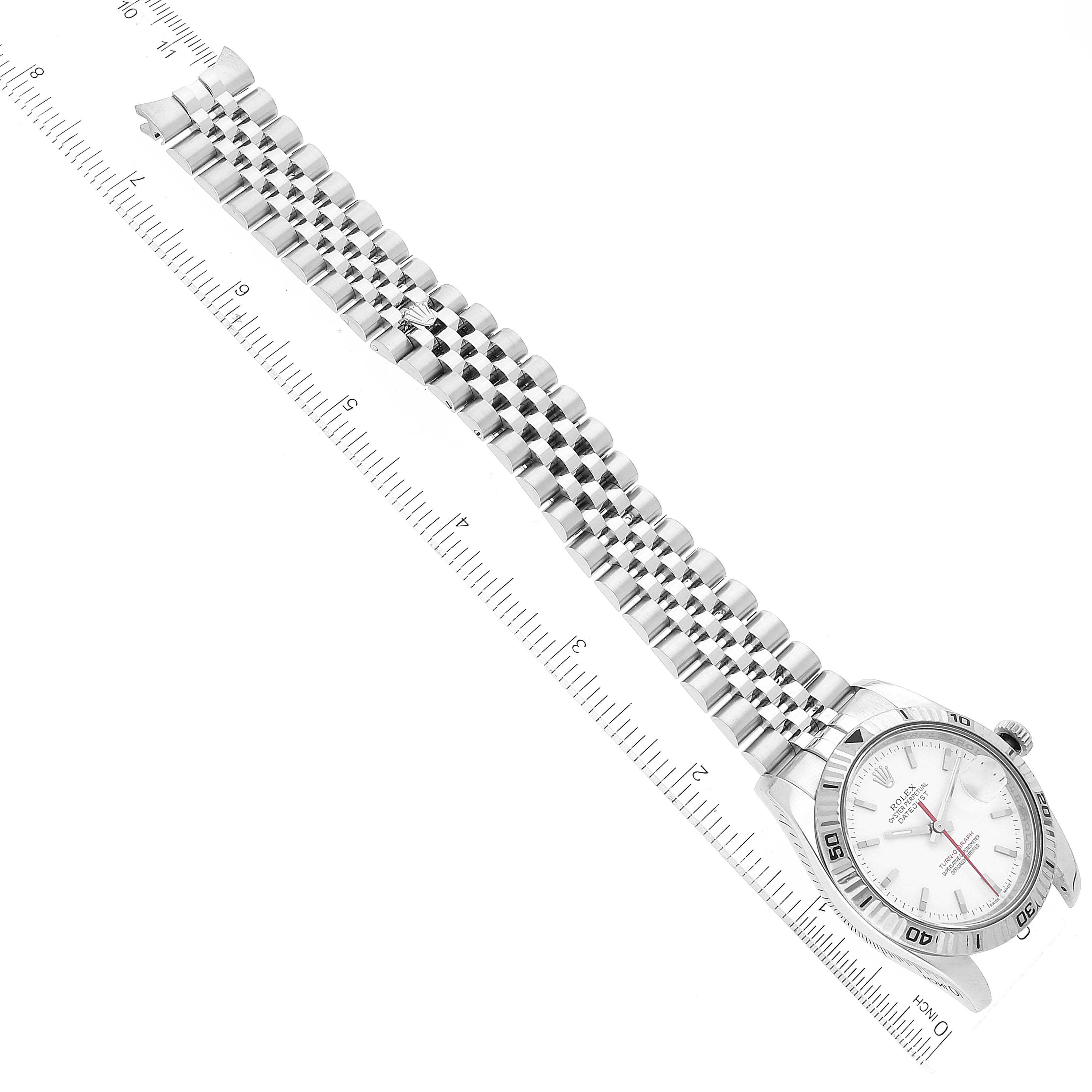 This image shows a Rolex Turn-o-Graph 116264 Men's Stainless Steel White Dial 116264 Men's Stainless Steel White Dial watch from an overhead angle, highlighting its face and bracelet in full extension near a ruler.