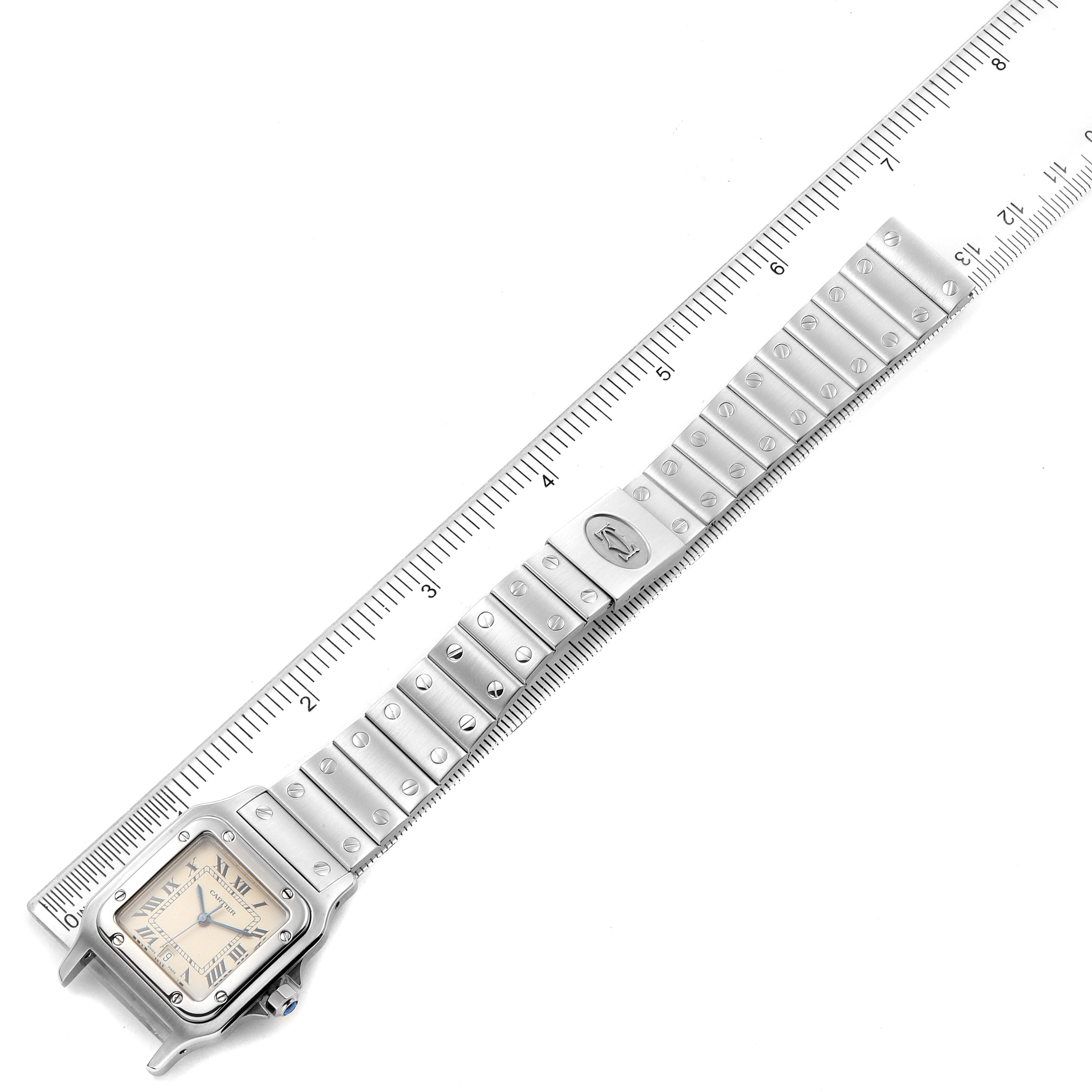 The image shows a Santos model watch by Cartier, laid flat with a ruler beside it to display its length.