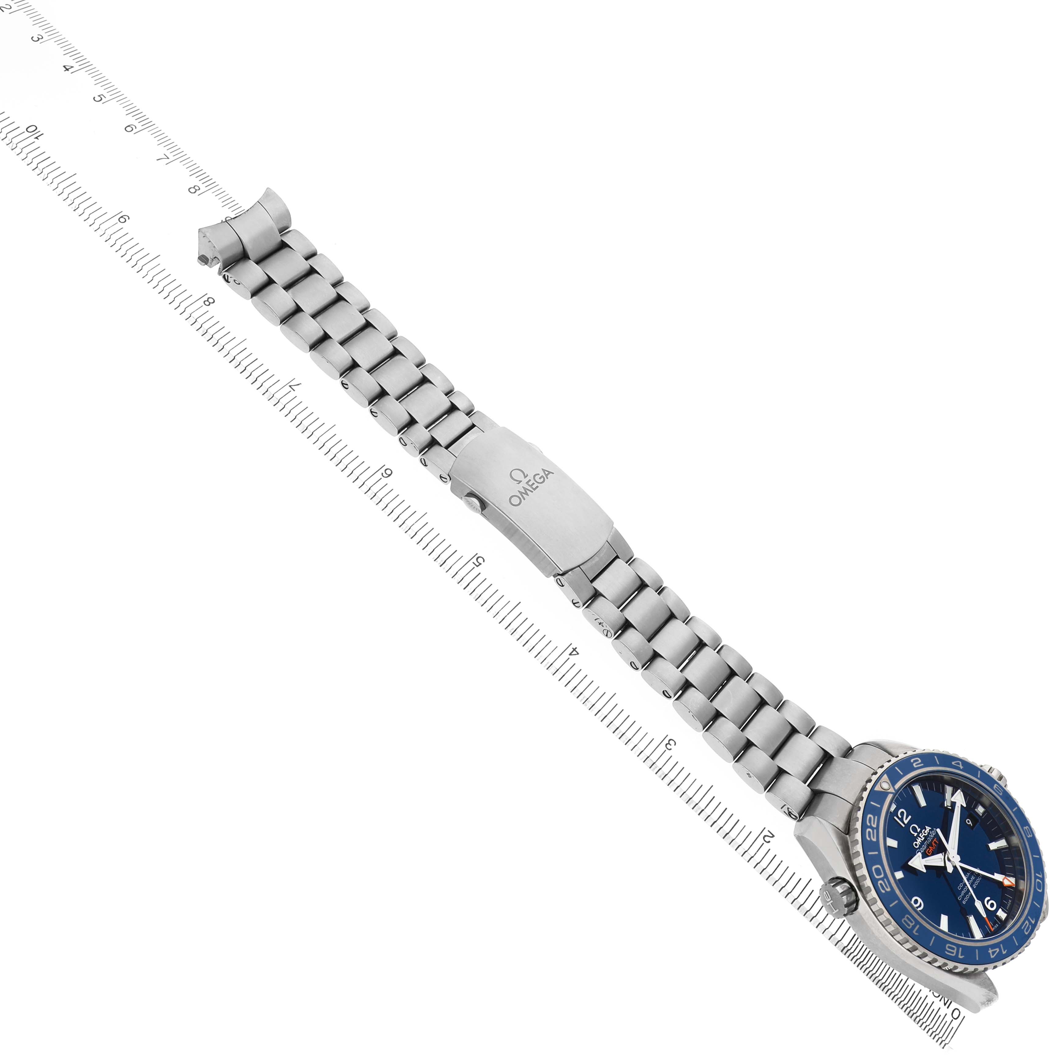 The Omega Planet Ocean 232.90.44.22.03.001 Men's Stainless Steel Blue Dial watch is shown at an angle displaying the face, bracelet, and clasp along a measuring ruler.