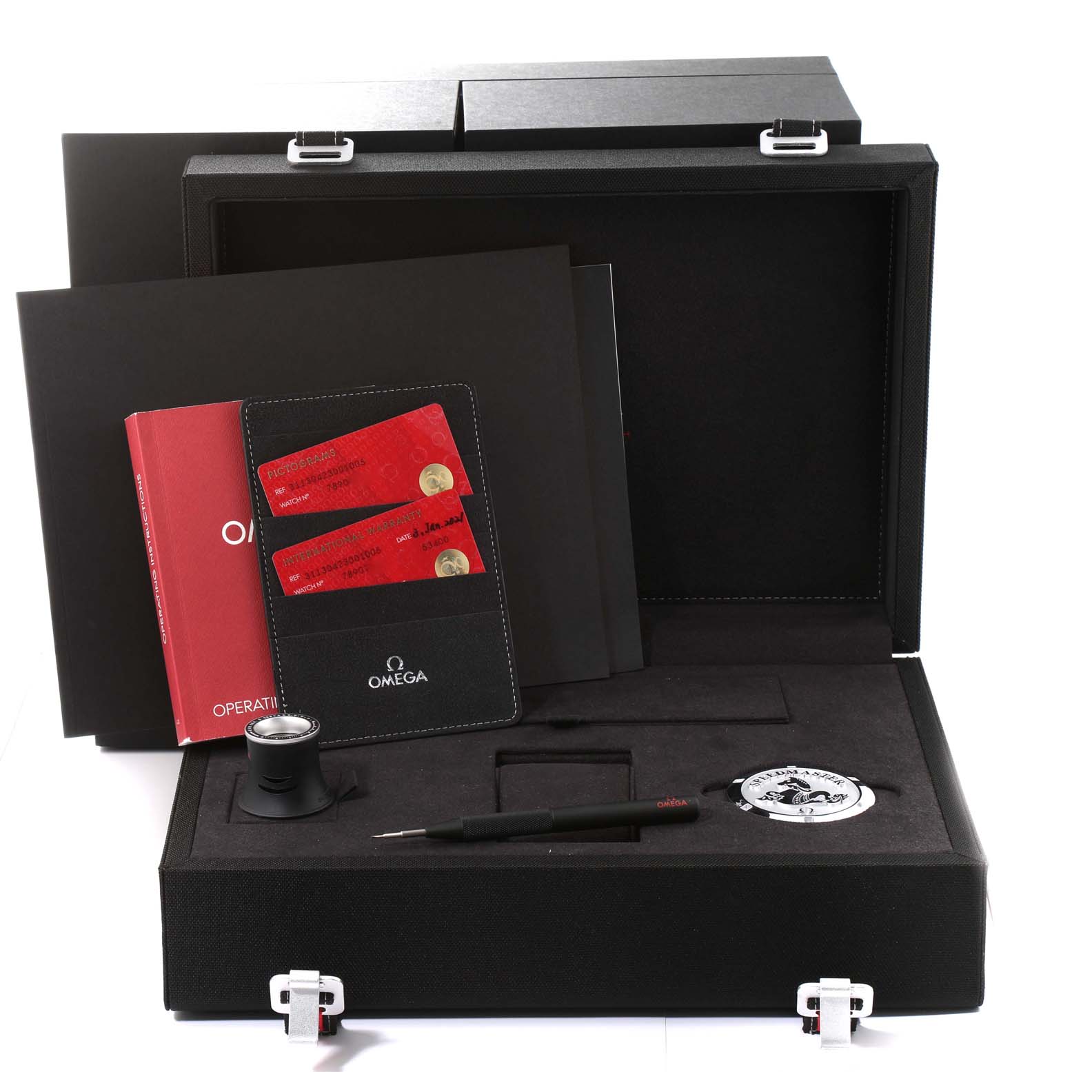 The image shows the accessories of the Omega Speedmaster 311.30.42.30.01.005 Men
s Stainless Steel Black Dial 311.30.42.30.01.005 Men
s Stainless Steel Black Dial watch including a manual, cards, loupe, tool, and commemorative coin, in a display case.