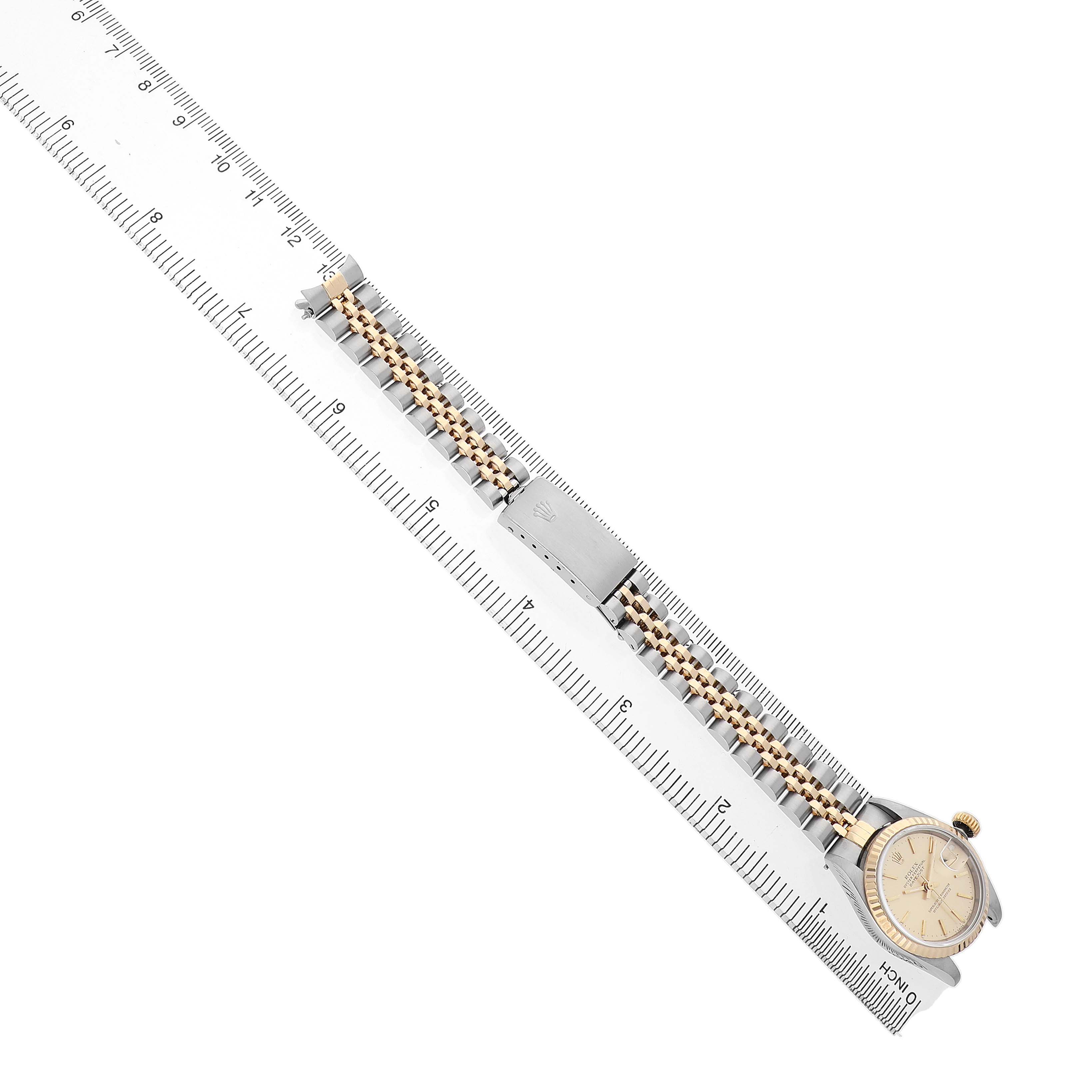 The Rolex Datejust 69173 Men's Steel and Gold (two tone) Champagne Dial watch is shown at an angle with a focus on the bracelet and clasp, alongside a ruler for scale.