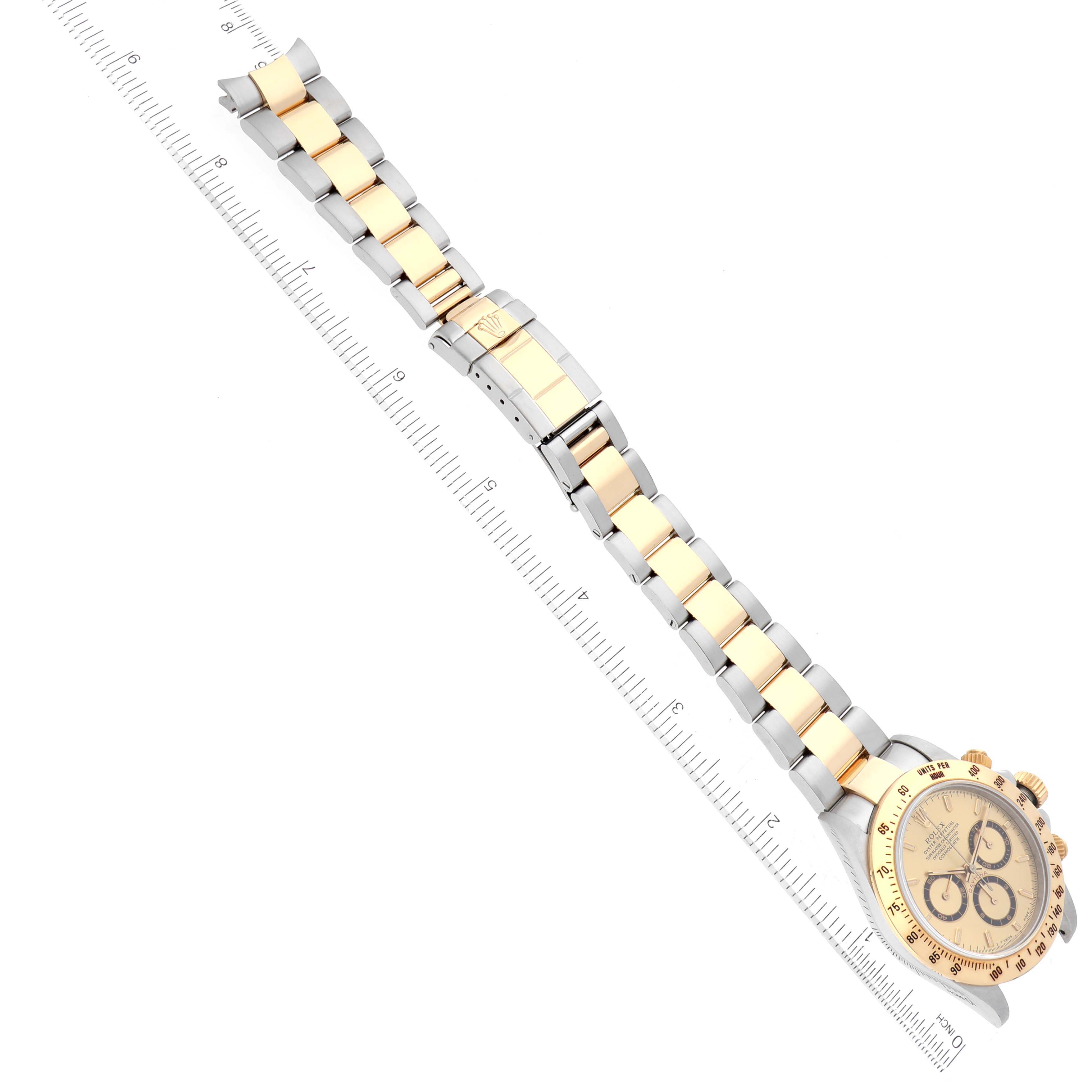 The image shows a Rolex Daytona 16523 Men's Steel and Gold (two tone) Champagne Dial 16523 Men's Steel and Gold (two tone) Champagne Dial watch, featuring its full face and bracelet laid out next to a ruler.