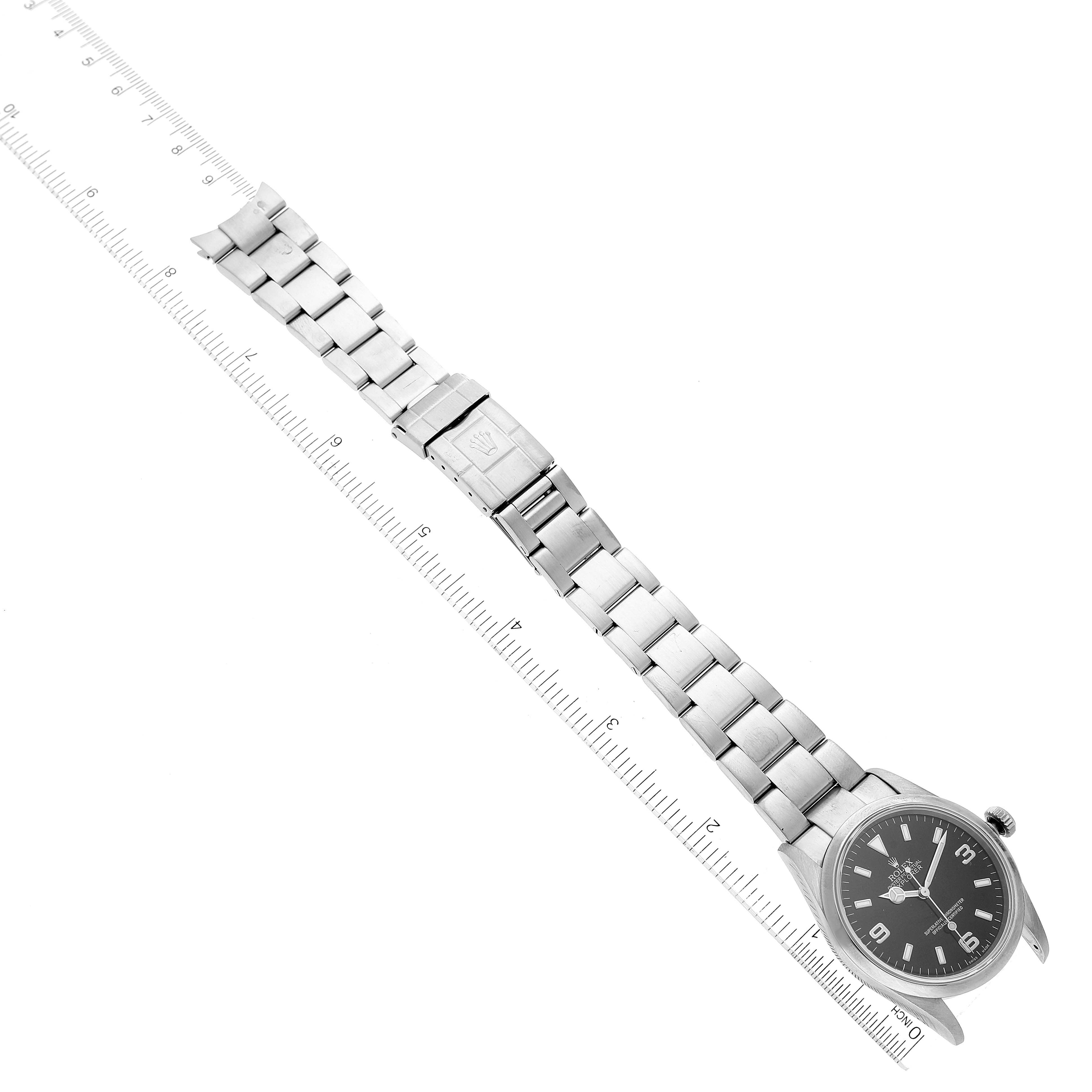 This image shows the entire Rolex Explorer 114270 Men
s Stainless Steel Black Dial 114270 Men
s Stainless Steel Black Dial watch, including the face, bracelet, and clasp, laid flat next to a ruler.