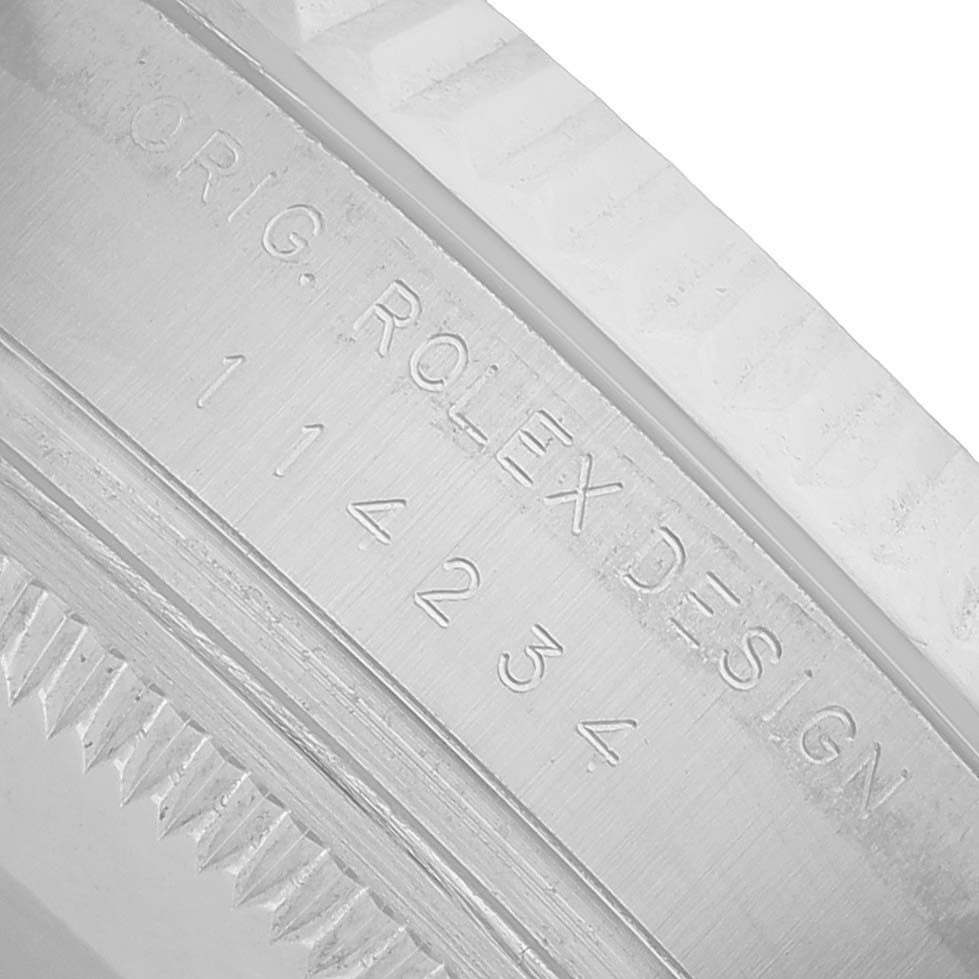 The image shows a close-up of the engraved bezel edge and serial number on a Rolex Air-King 114234 Men's Stainless Steel Pink Dial watch.