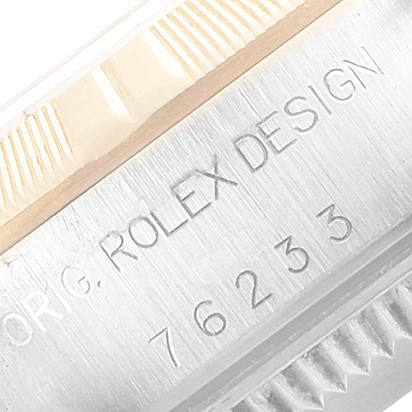 The image shows a close-up of the side of a Rolex Oyster Perpetual 76233 Women's Steel and Gold (two tone) Black Dial 76233 Women's Steel and Gold (two tone) Black Dial watch, highlighting the engraved text and part of the bezel.