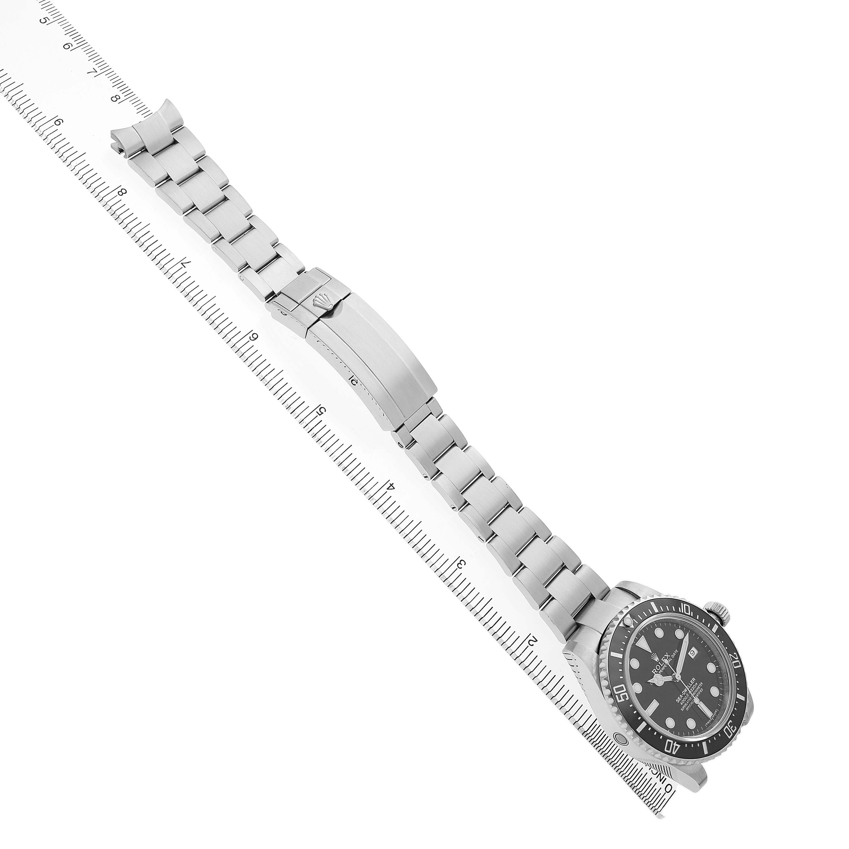 The Rolex Sea-Dweller 116600 Men's Stainless Steel Black Dial watch is shown from a top view, displaying the full bracelet and watch face alongside a measuring scale.