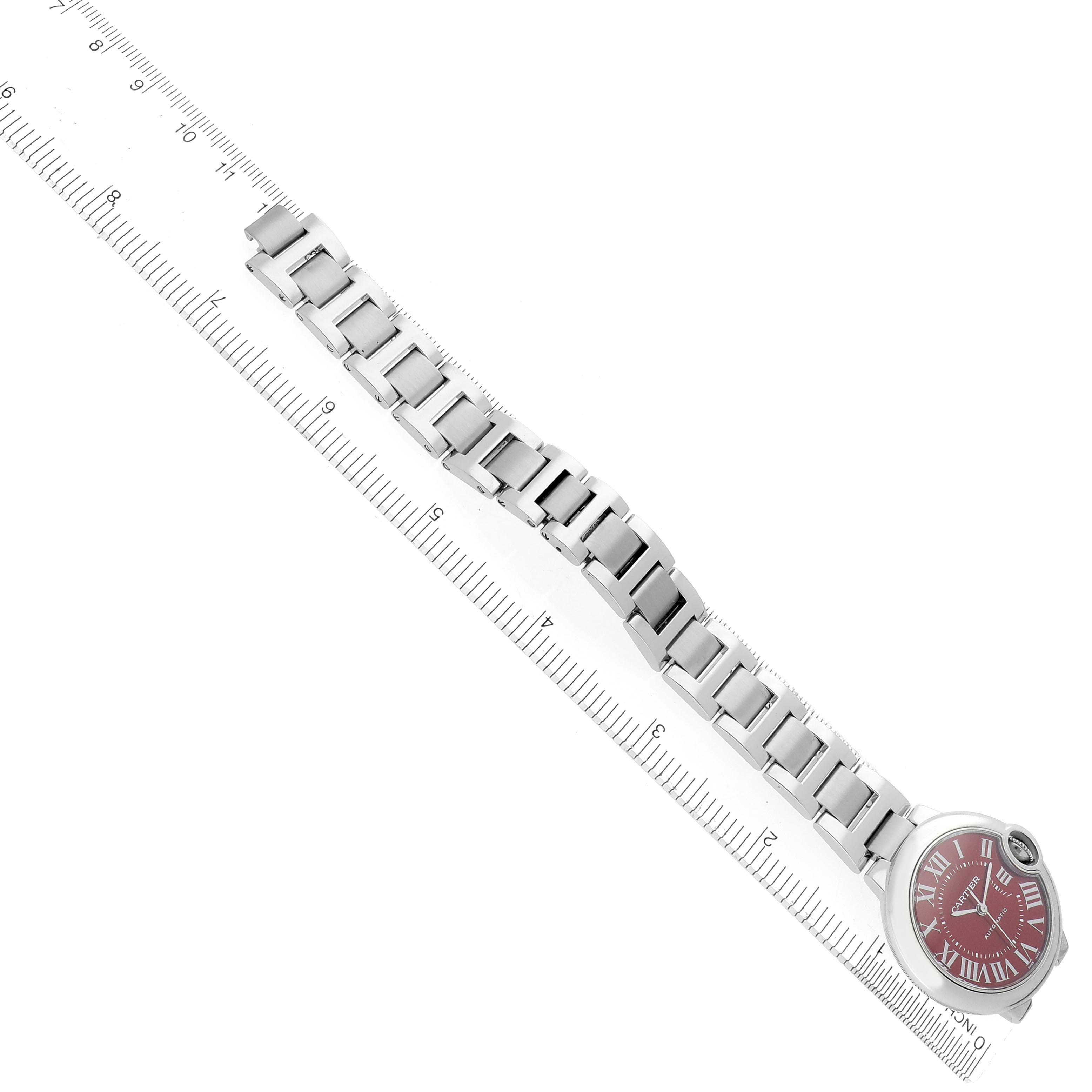 The Cartier Ballon Bleu WSBB0052 Women's Stainless Steel Red Dial WSBB0052 Women's Stainless Steel Red Dial watch is shown from a top view, displaying the entire bracelet and face with a ruler beside it.
