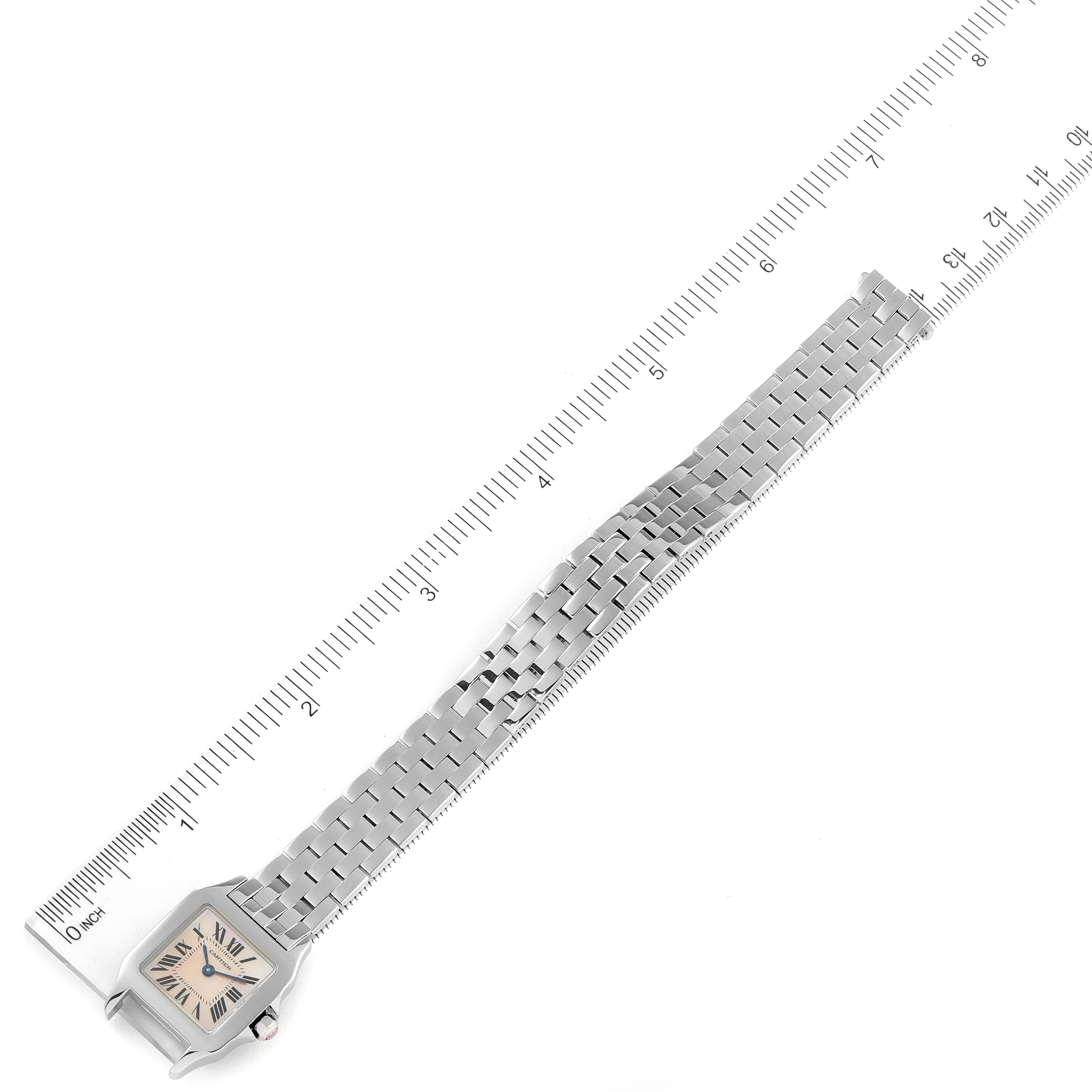 The image shows a top-down view of the Santos Demoiselle watch by Cartier, including the face, bezel, and full metal bracelet next to a ruler.