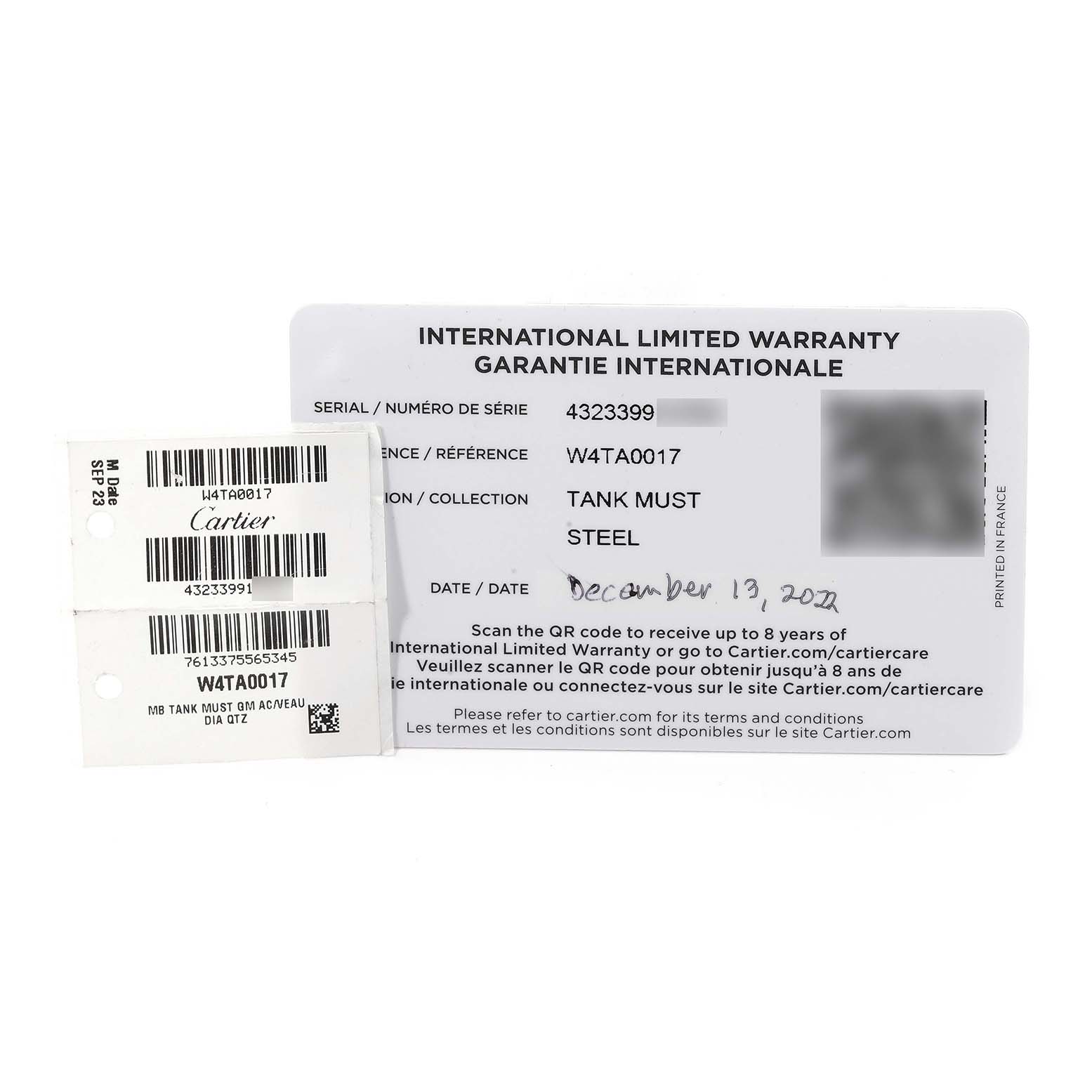 The image shows the international limited warranty card and tags of the Cartier Tank Must W4TA0017 Women
s Stainless Steel Silver Dial W4TA0017 Women
s Stainless Steel Silver Dial watch model.