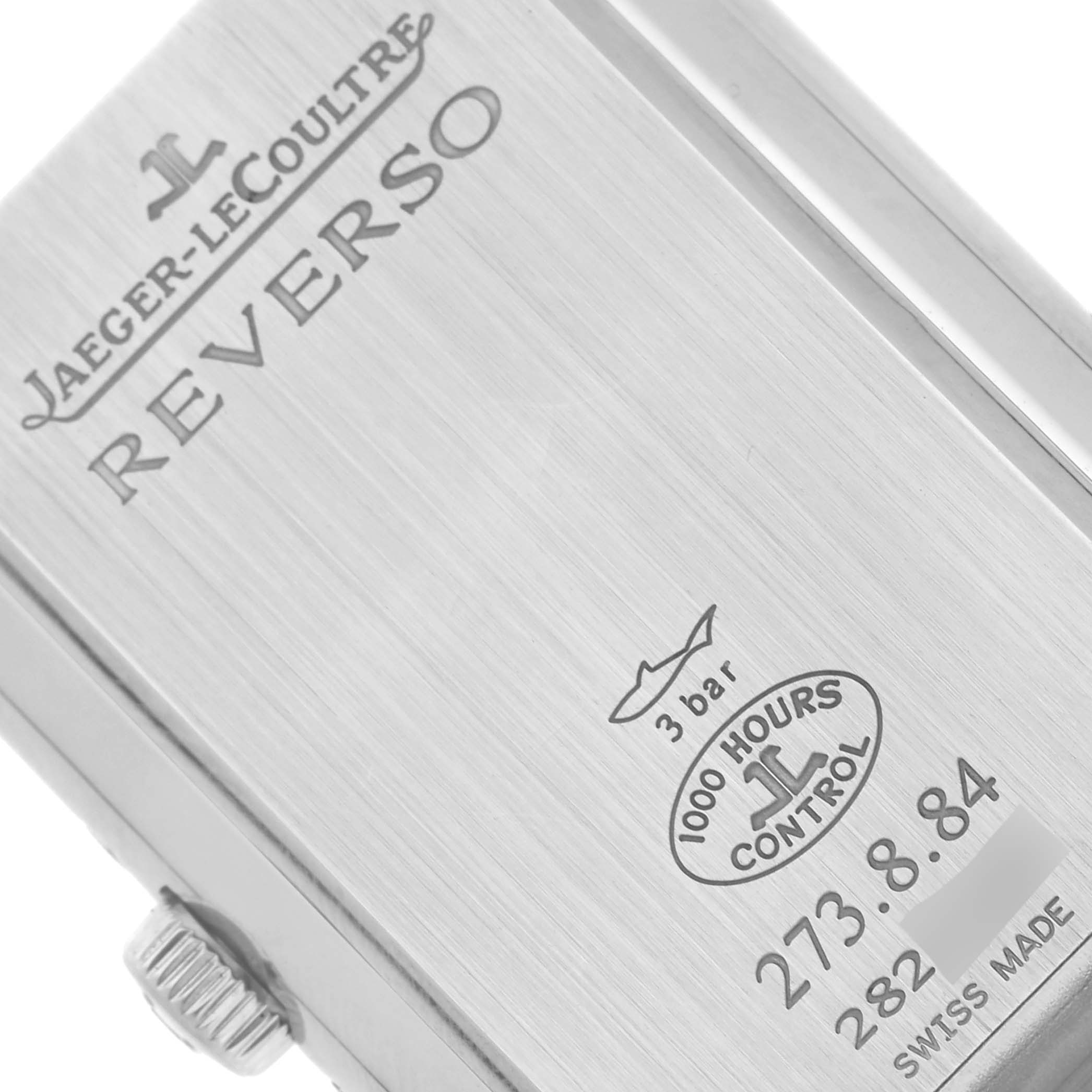 The image shows the back of a Jaeger-LeCoultre Reverso watch at a slight angle, featuring branding, water resistance, and control marks.