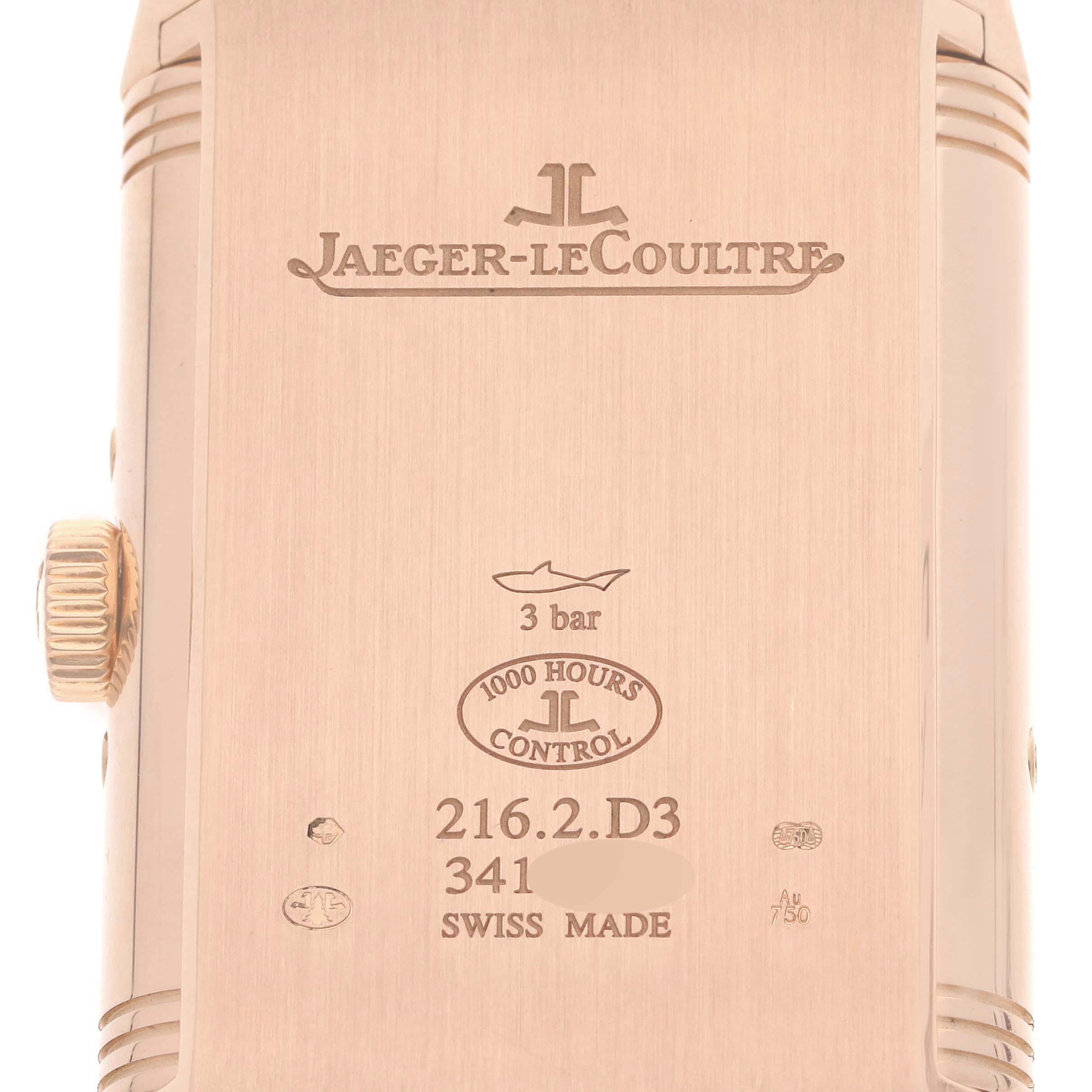 The image shows the back case of a Jaeger-LeCoultre Reverso watch, featuring engravings and the crown on the left side.