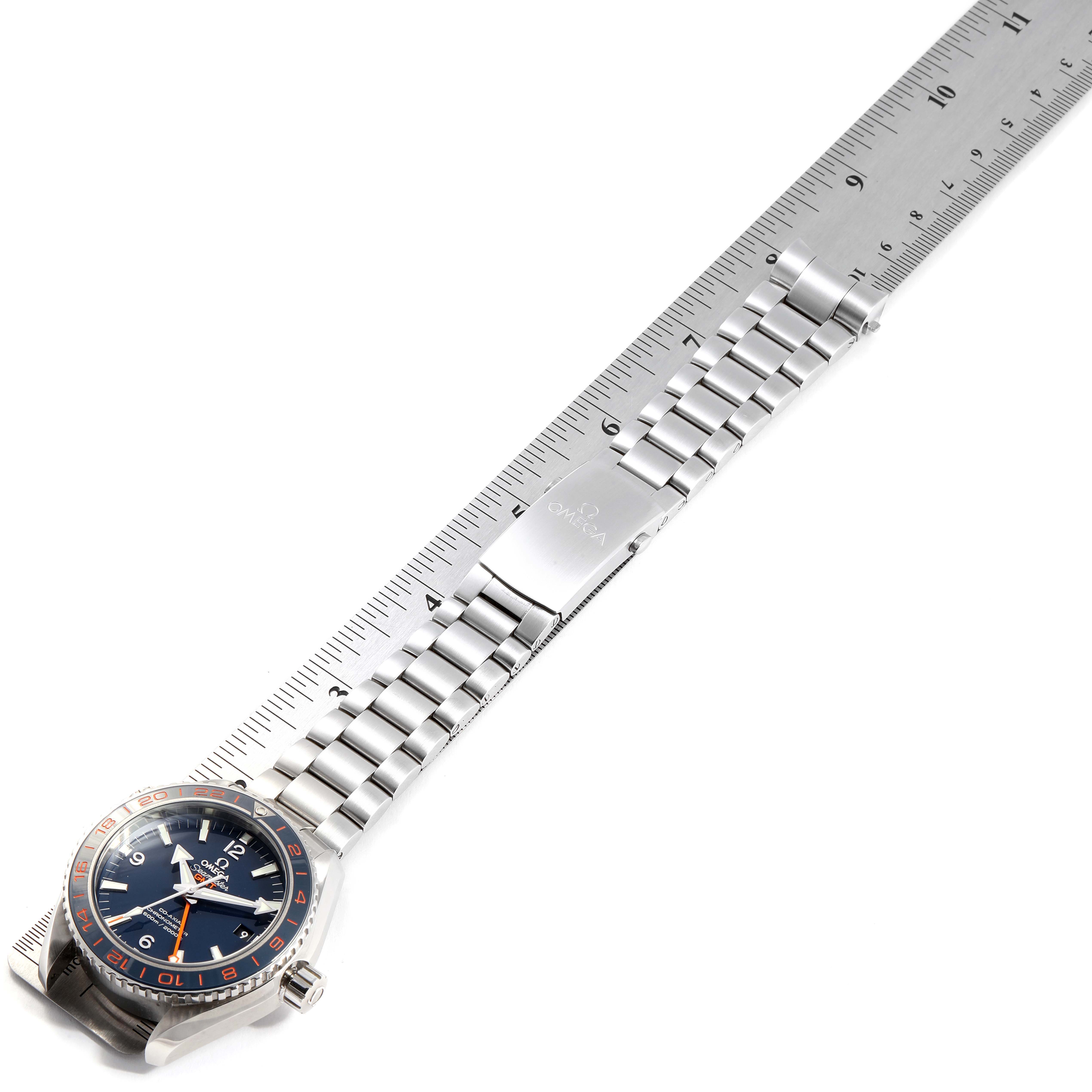 The Omega Planet Ocean 232.30.44.22.03.001 Men's Stainless Steel Blue Dial 232.30.44.22.03.001 Men's Stainless Steel Blue Dial watch is shown from a top-down angle, featuring its face and metal bracelet stretched alongside a ruler.