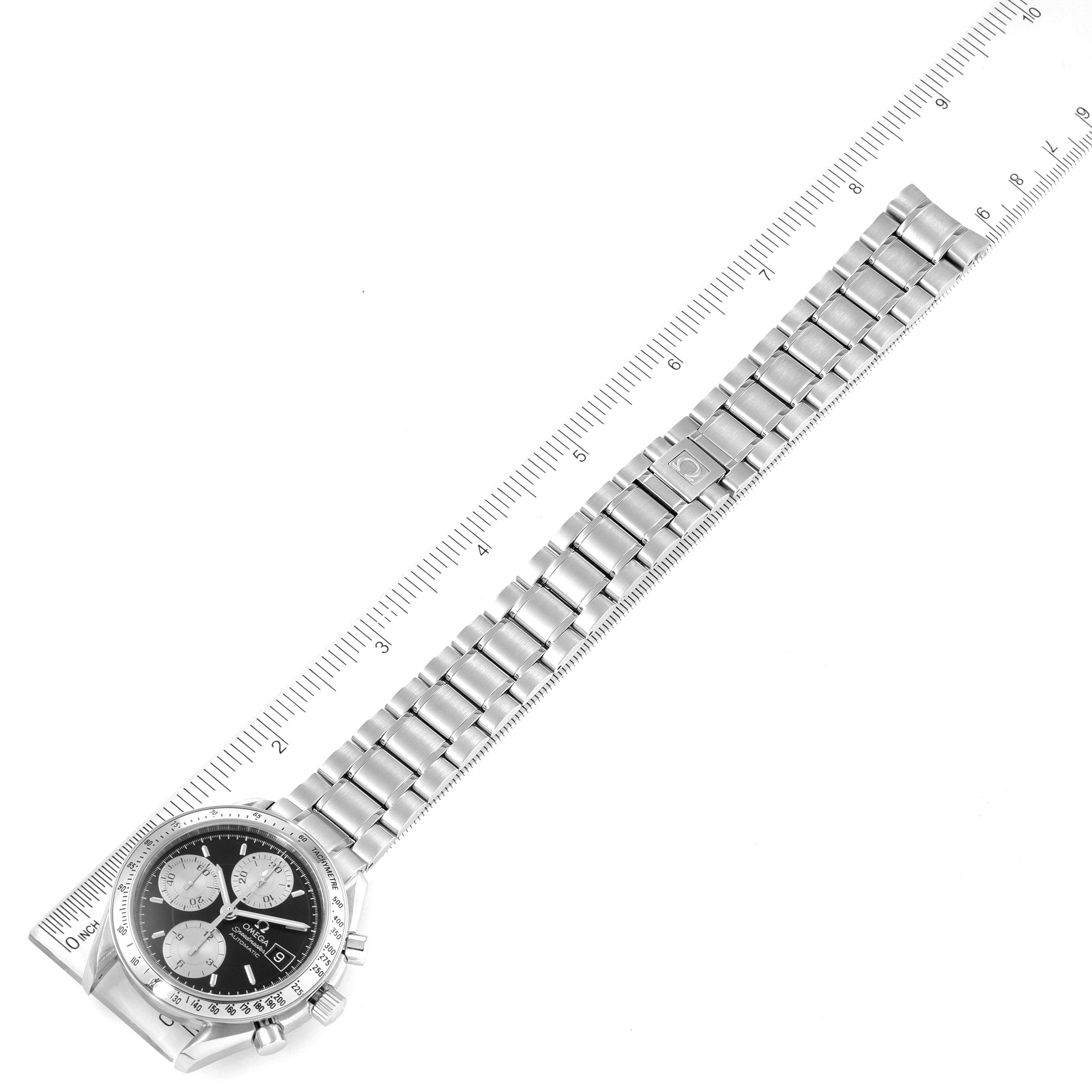 The image shows an Omega Speedmaster 3513.51.00 Men
s Stainless Steel Black Dial 3513.51.00 Men
s Stainless Steel Black Dial watch at an angled top-down view, with its full stainless steel bracelet extended next to a ruler.
