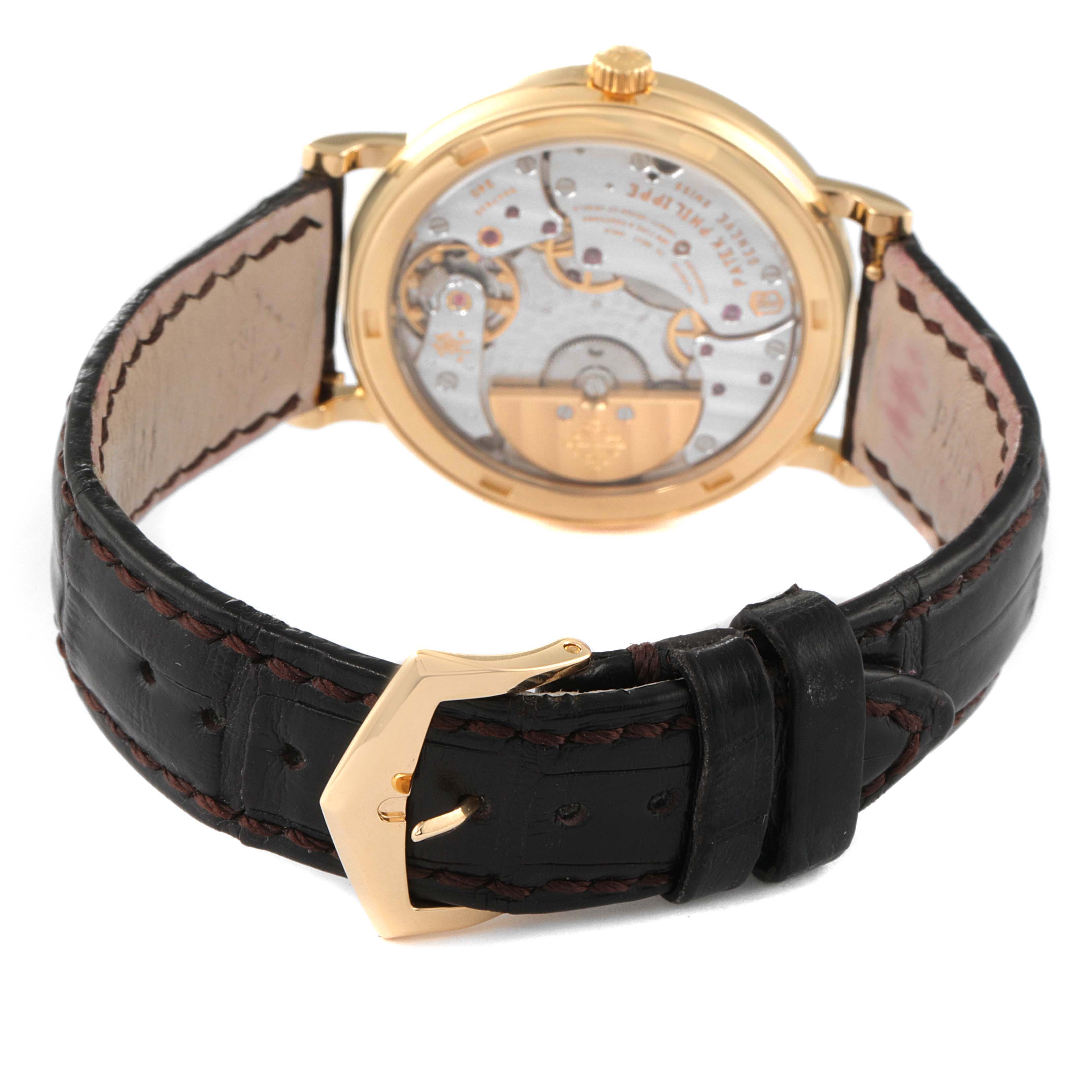 The image shows the back view of a Patek Philippe Calatrava 5120J Men
s Yellow Gold White Dial 5120J Men
s Yellow Gold White Dial watch, highlighting the movement and the leather strap with a gold buckle.